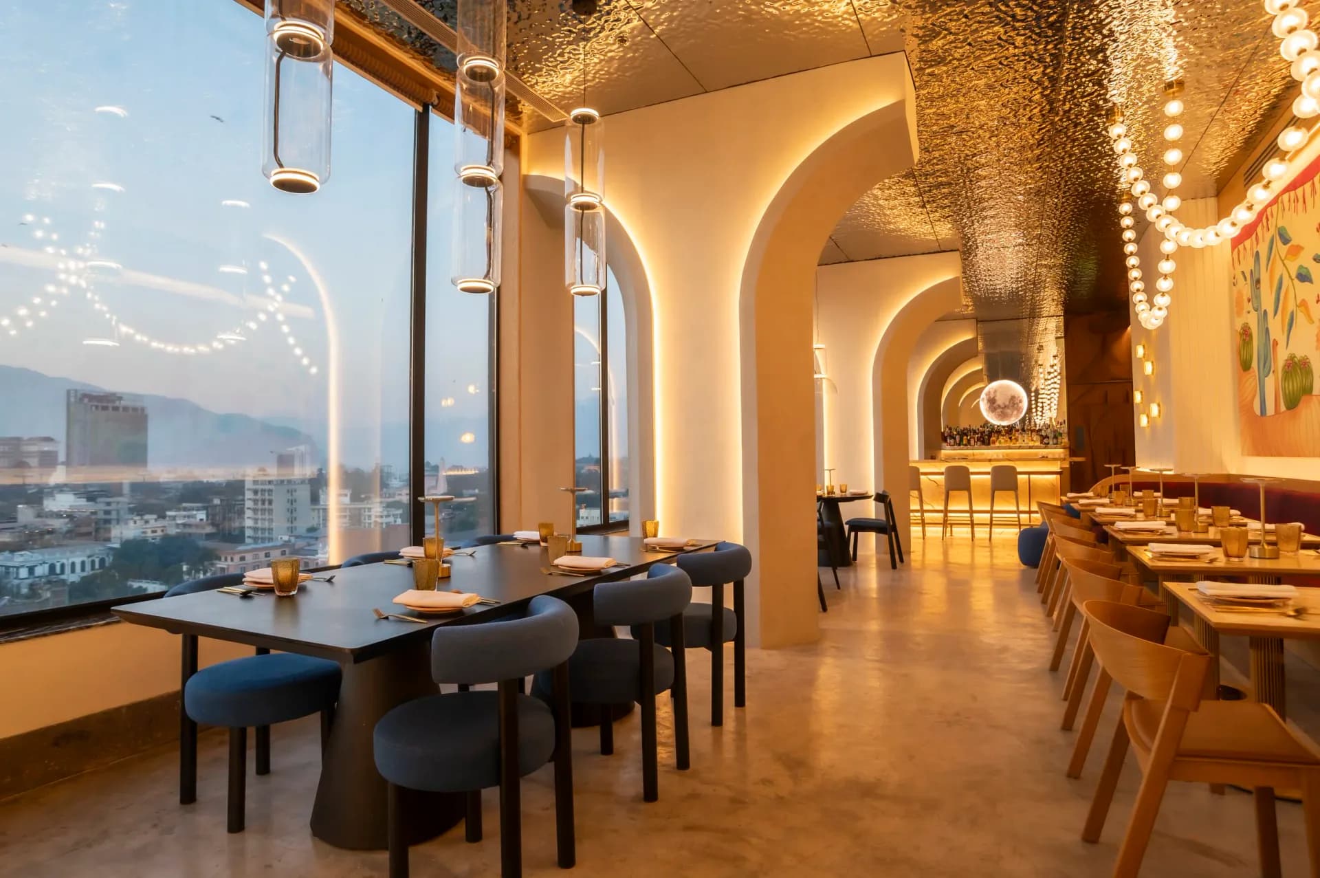 Upscale restaurant interior with arched ceilings, warm golden lighting, floor-to-ceiling windows overlooking cityscape, and modern dining furniture by Pablo Castellanos.