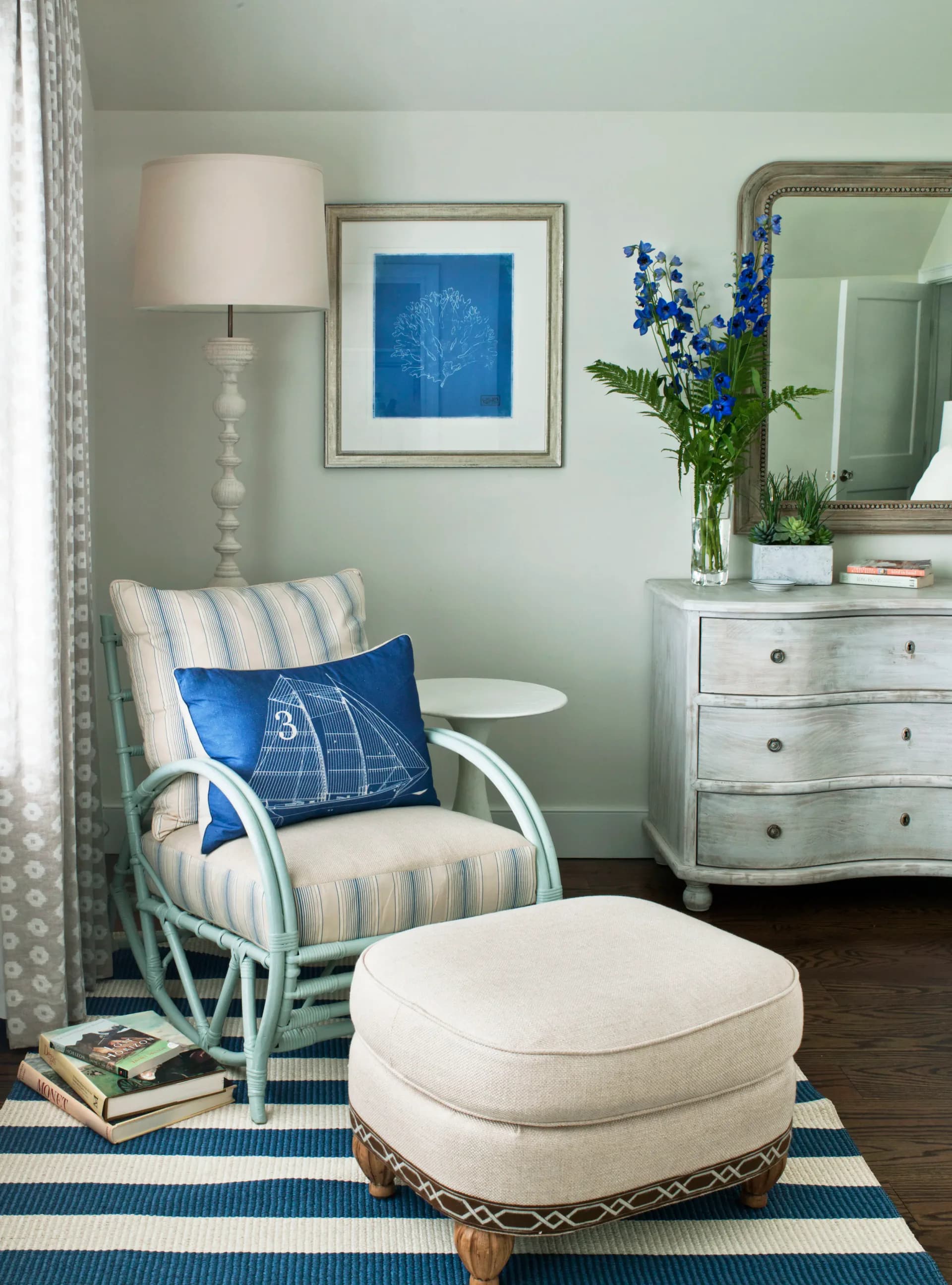 Serene bedroom corner with pale green walls, striped armchair, white ottoman, blue botanical artwork, and vintage dresser in soft neutral tones by Patricia McGrath.