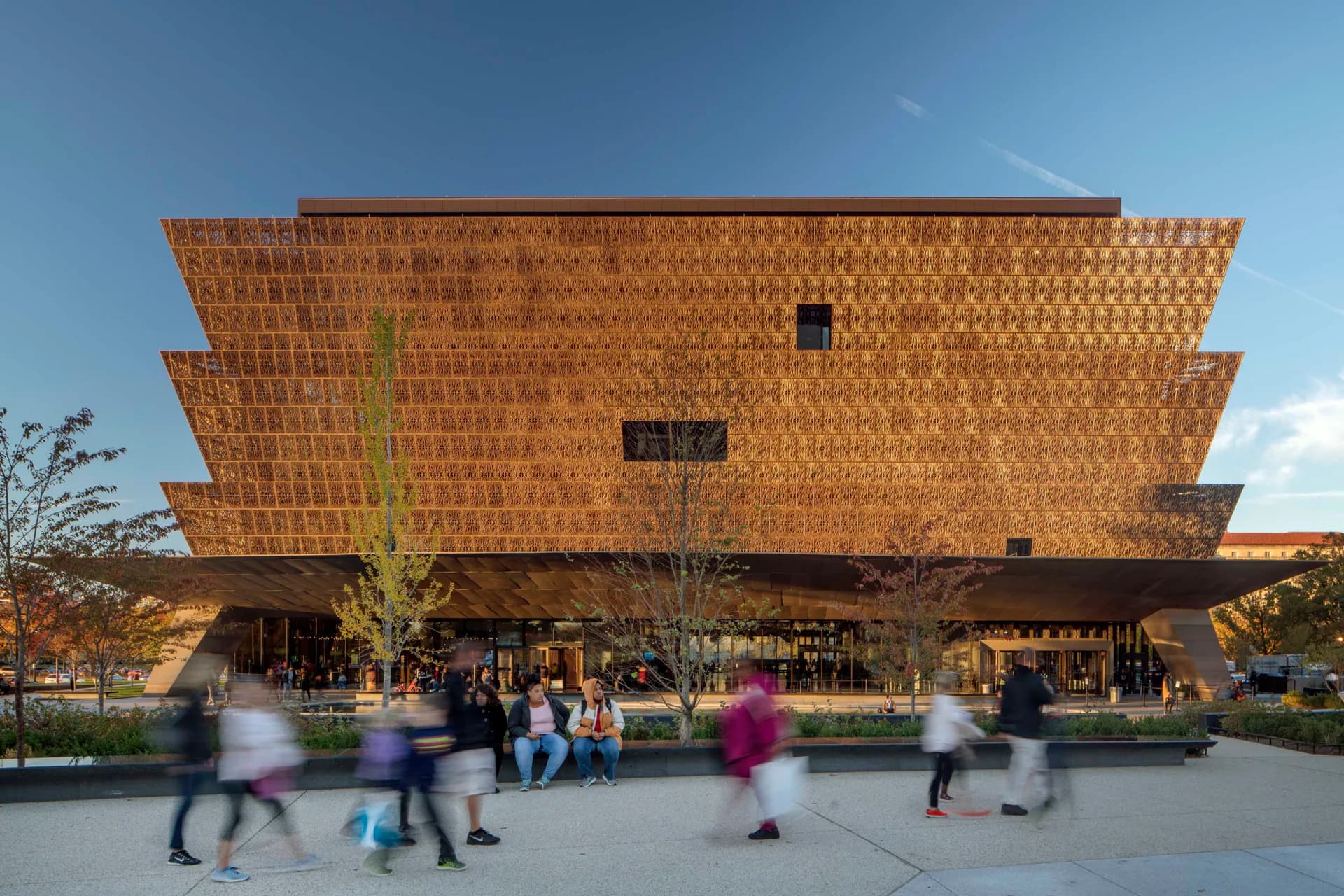 Brick-clad museum building with distinctive stepped architectural form, photographed during daytime with visitors in the plaza by Paula Sanchez.