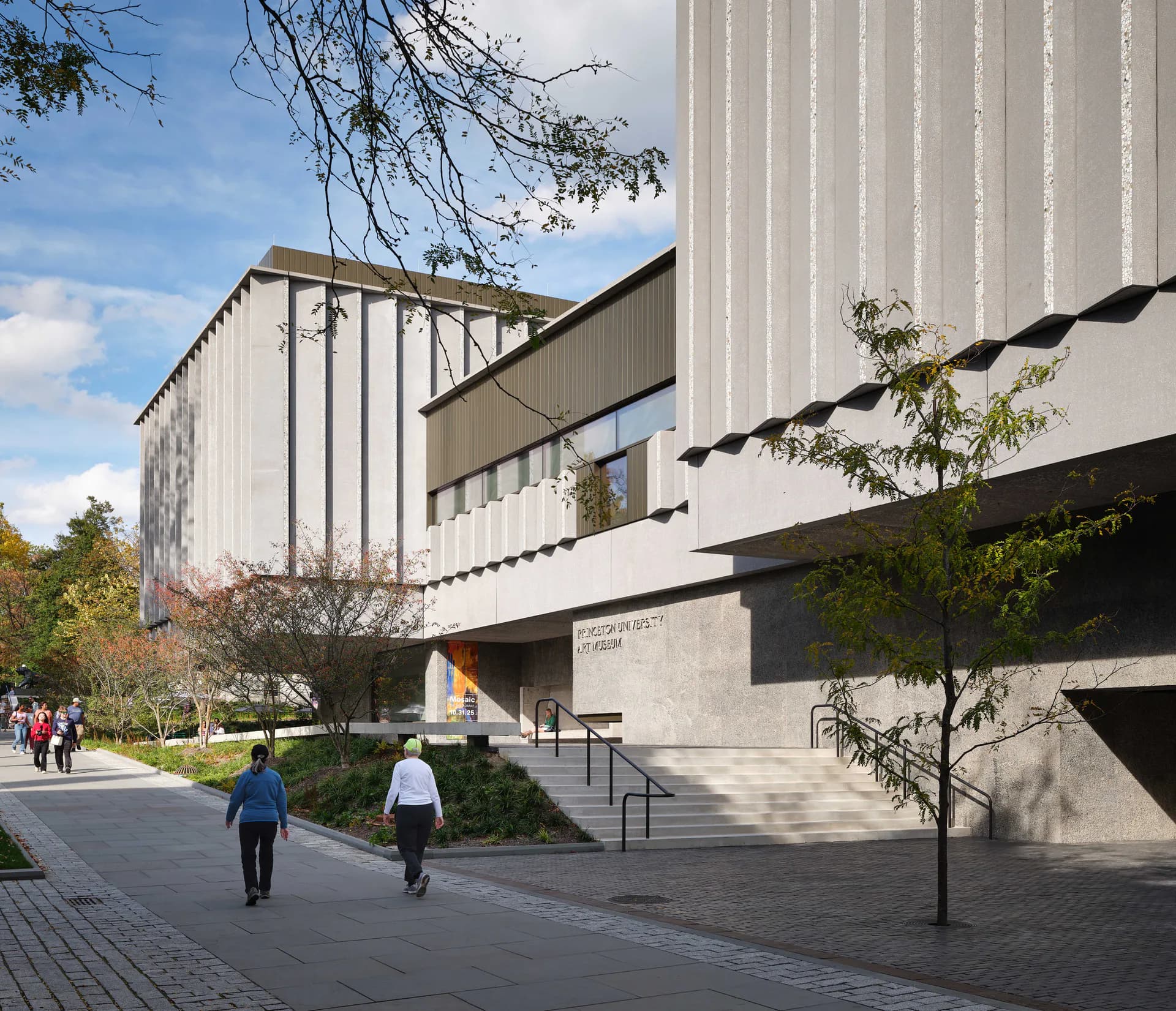 Modern institutional building exterior with vertical metal cladding, concrete elements, and contemporary architectural design by Paula Sanchez.