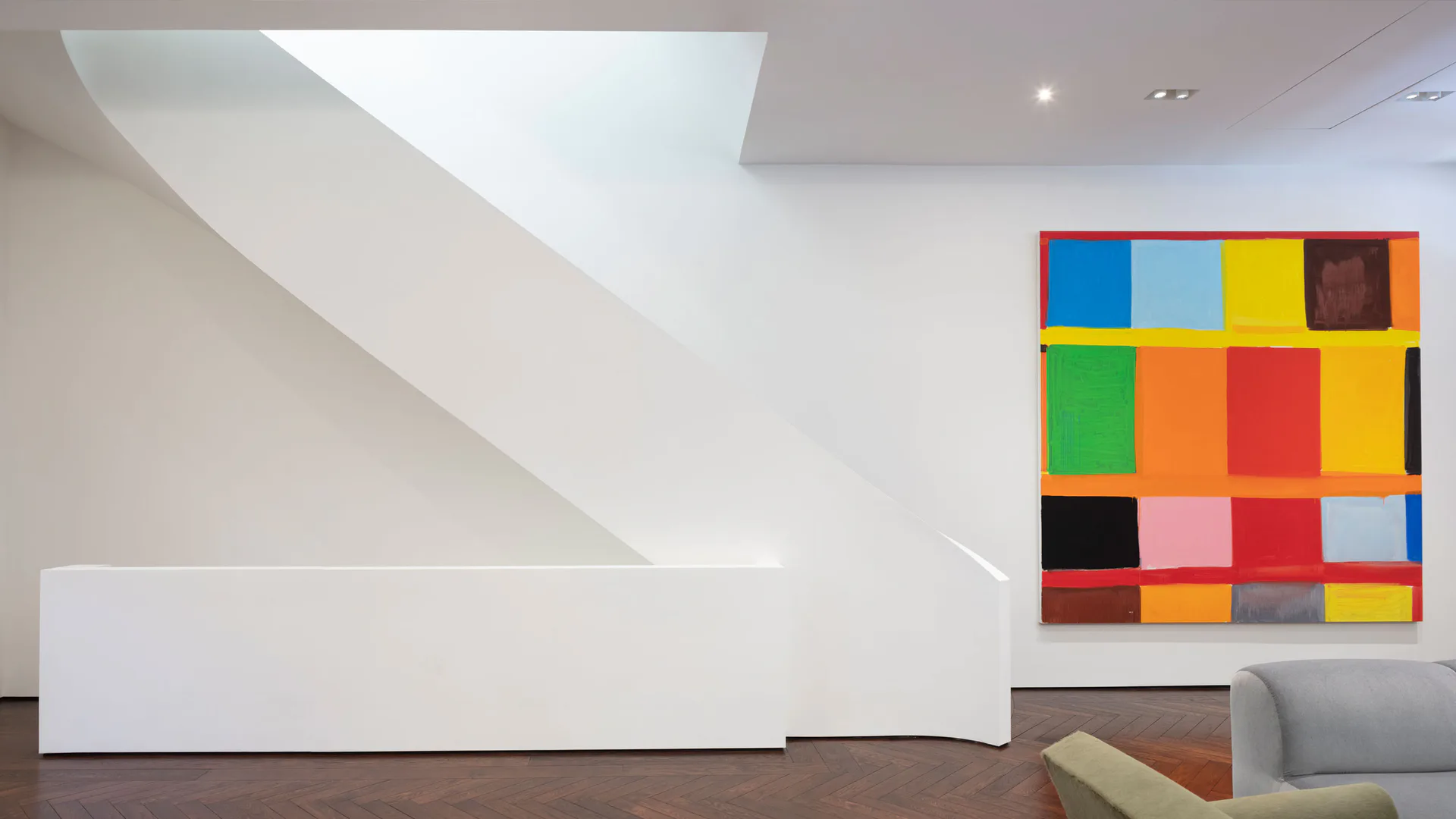 Modern gallery interior featuring curved white architectural elements, polished concrete flooring, and a colorful grid artwork installation by Peter Stamberg.