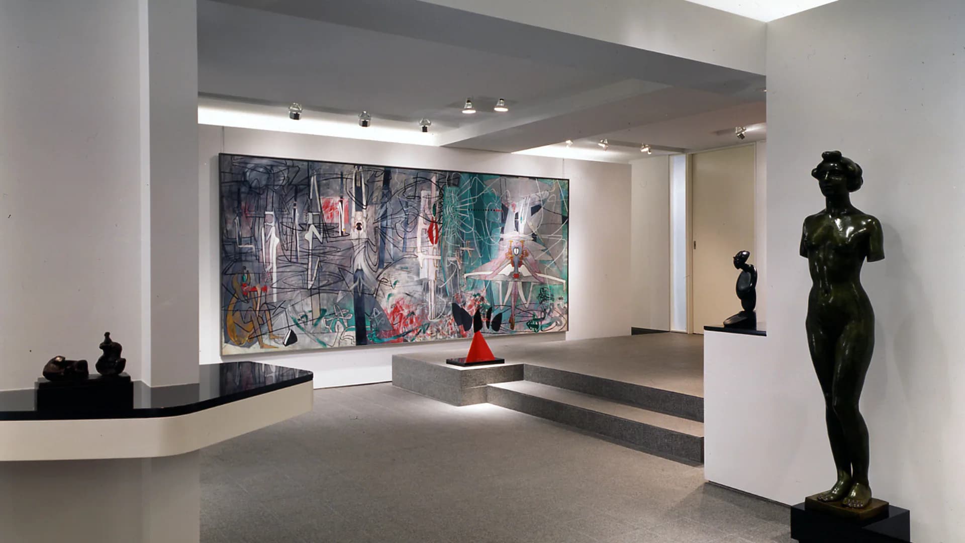 Modern gallery interior with polished concrete floors, white walls, and sculptural black figures; large abstract painting displayed on rear wall by Peter Stamberg.