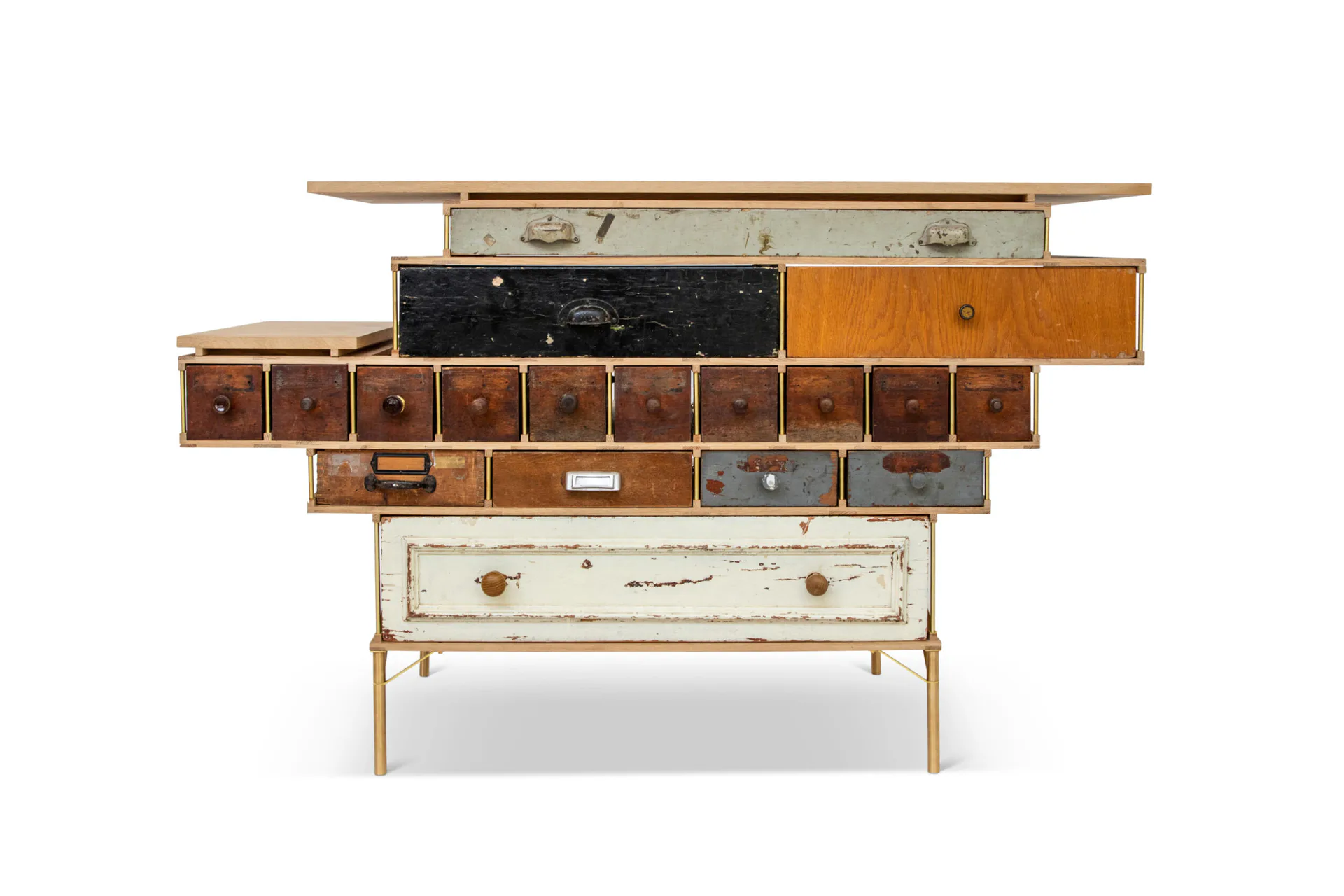 Stacked wooden cabinet furniture piece with varied drawer sizes, natural wood tones, and mixed materials including dark and light finishes by Piet Hein Eek.