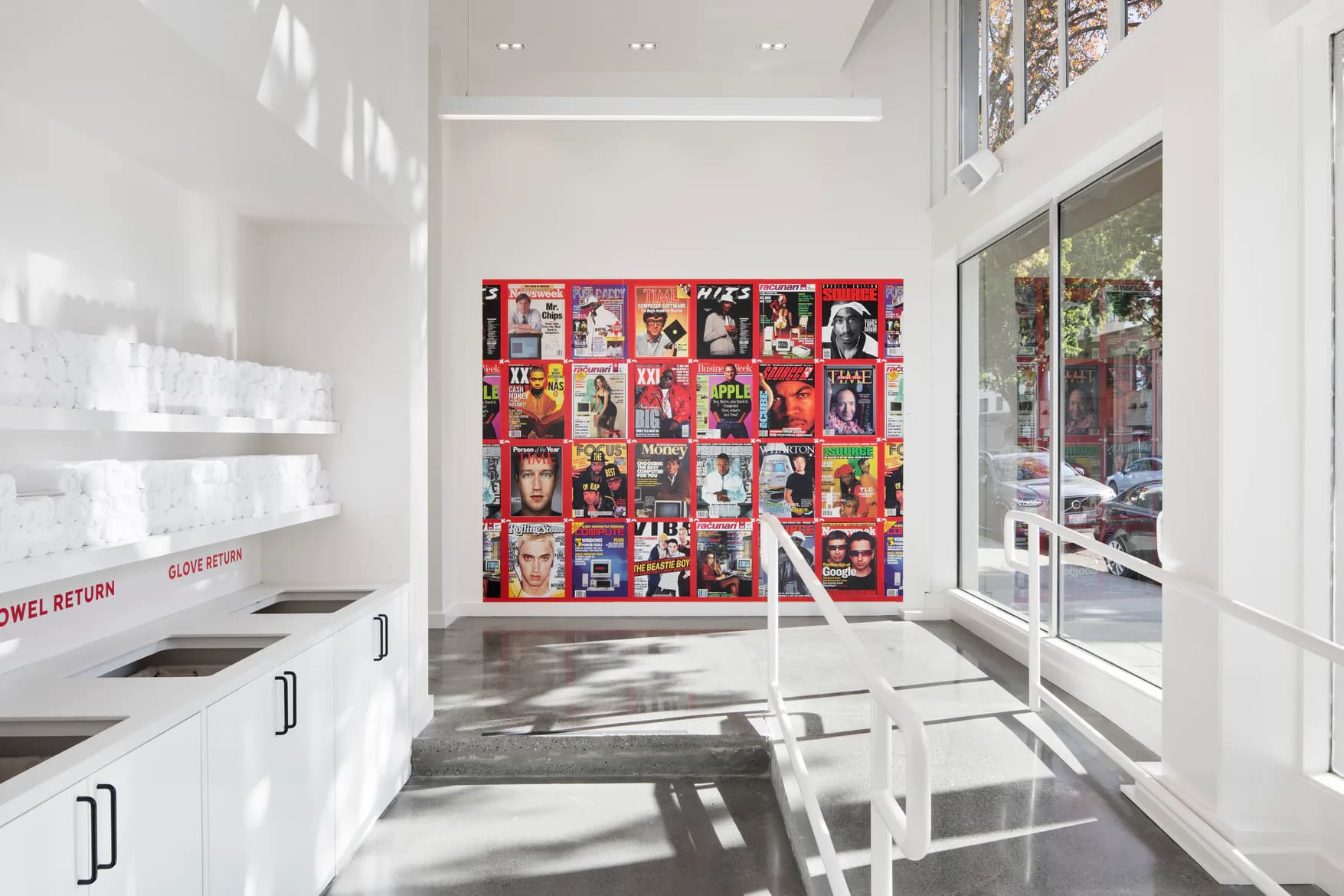 Modern retail interior with white cabinetry, polished concrete floors, and a vibrant red photo wall installation, designed by Rachel Robarge.