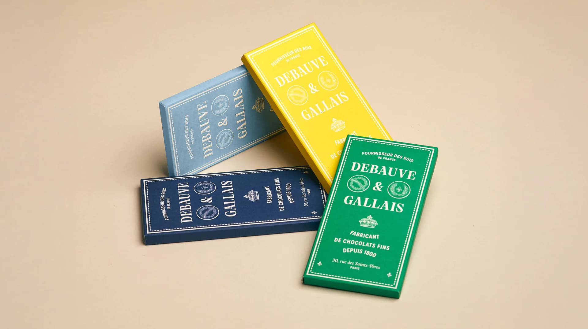 Stack of four decorative book spines with French titles and ornate designs in blue, yellow, and green, photographed against a neutral background by Reynald Philippe.