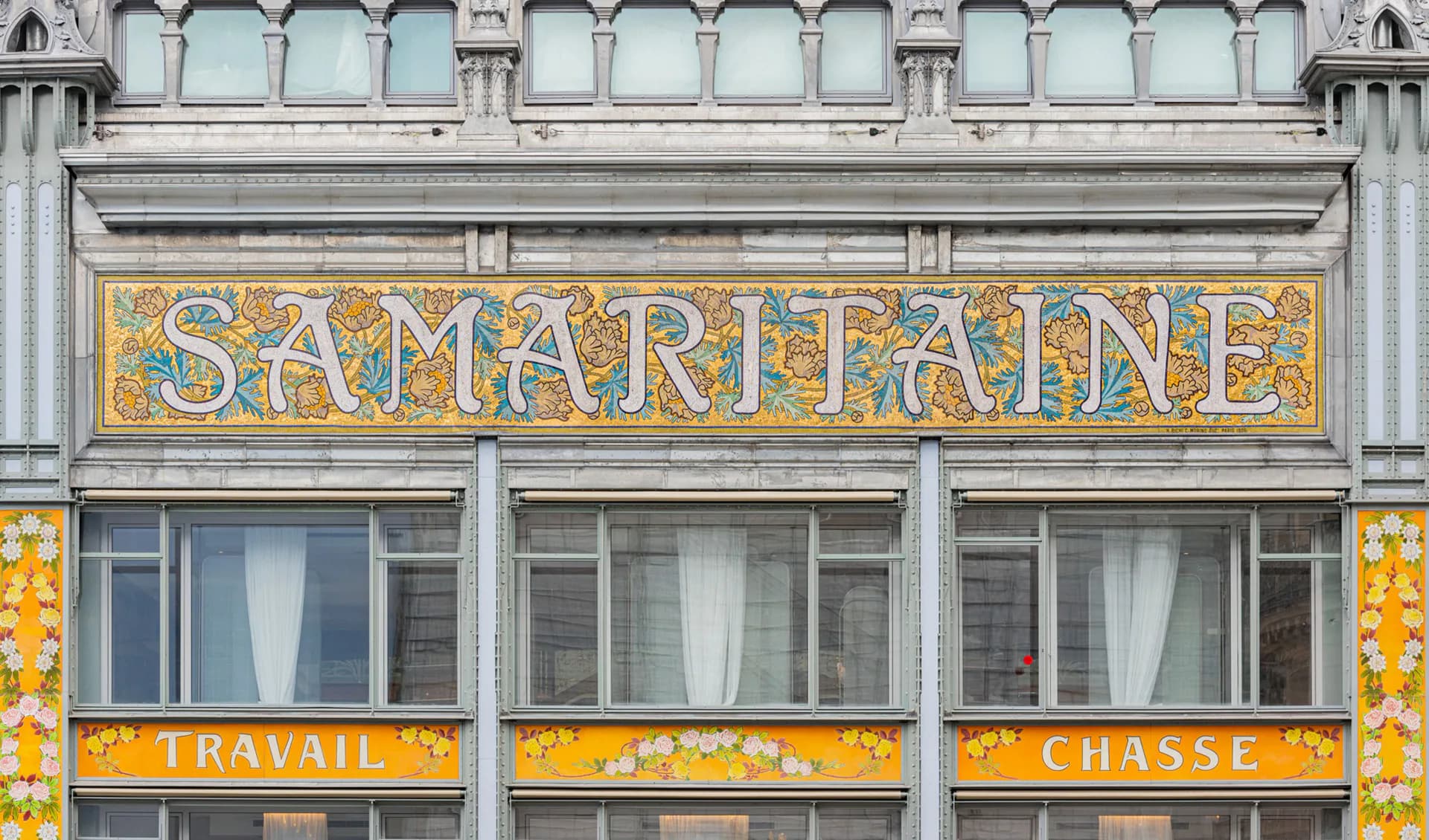Historic Samaritaine storefront with ornate stone facade, gilded signage, and yellow decorative panels, architectural photography by Reynald Philippe.