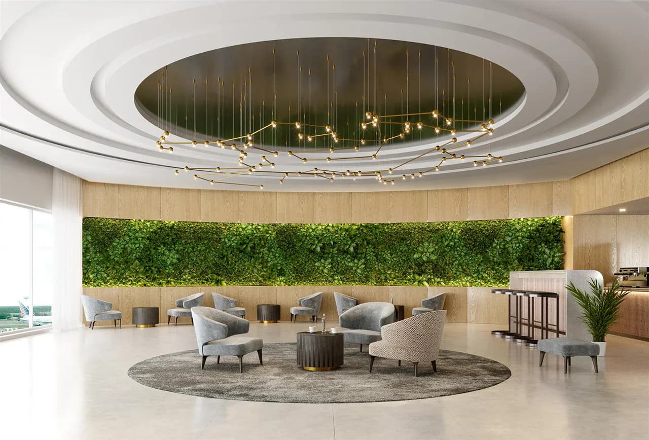 Circular hotel lobby with tiered white ceiling, central pendant lighting fixture, green living wall, warm wood tones, and upholstered seating by Richard Clarkson.