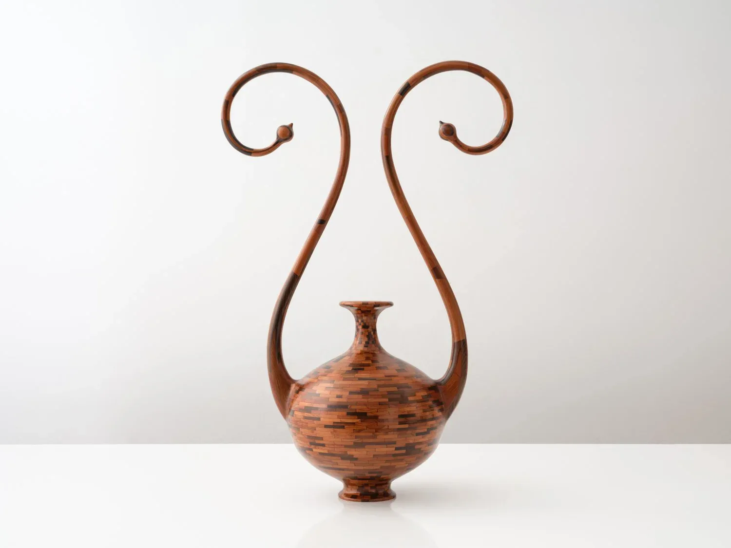 Wooden vessel with spherical body and slender neck, featuring elegant curved handles, crafted from figured wood by Richard Haining.