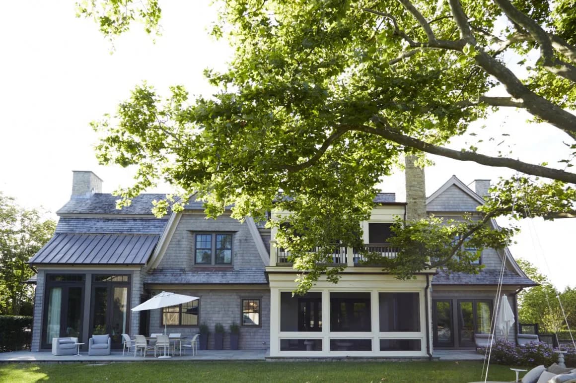 Modern residential home with dark exterior and large glass panels overlooking manicured lawn, designed by Rinat Lavi.