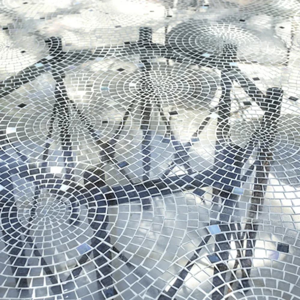 Intricate mosaic flooring featuring radial geometric patterns in black, white, and gray tiles arranged in concentric circles by Robert Nassar.