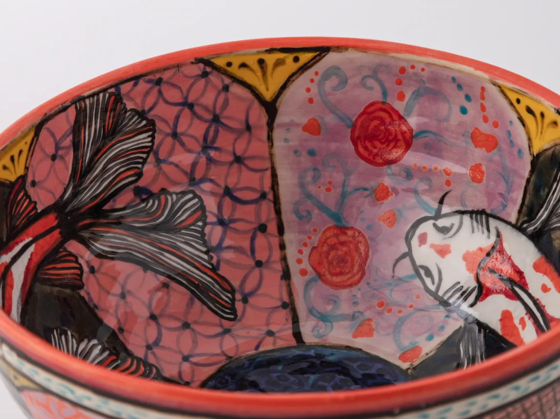 Ceramic bowl interior with hand-drawn black line illustrations, red and pink glaze, and decorative motifs by Roberto Lugo.