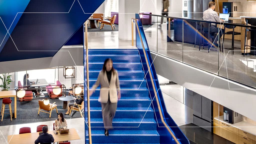Modern multi-level office atrium with striking blue stairs, geometric wall graphics, and open workspaces across tiered floors by Rocco Giannetti.