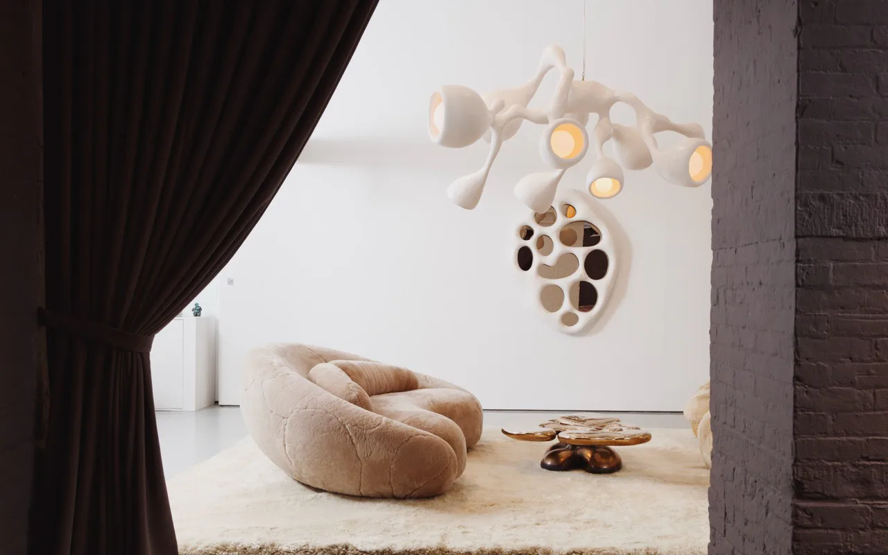 Minimalist interior with cream sculptural seating, natural wood flooring, and suspended organic pendant lighting installation by Rogan Gregory.