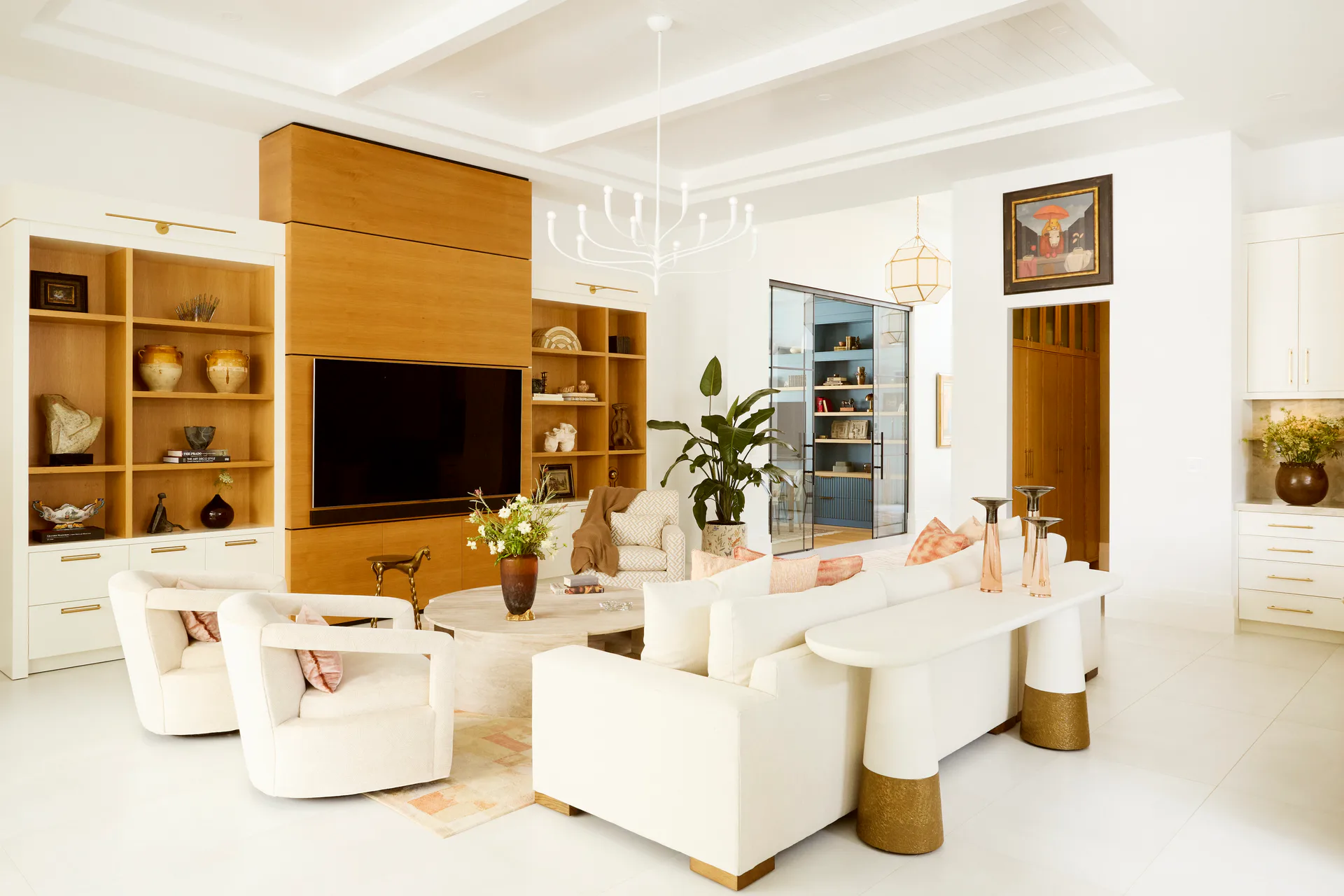 Modern living room with warm wood cabinetry, white seating, and natural materials, designed by Russell Goldman.