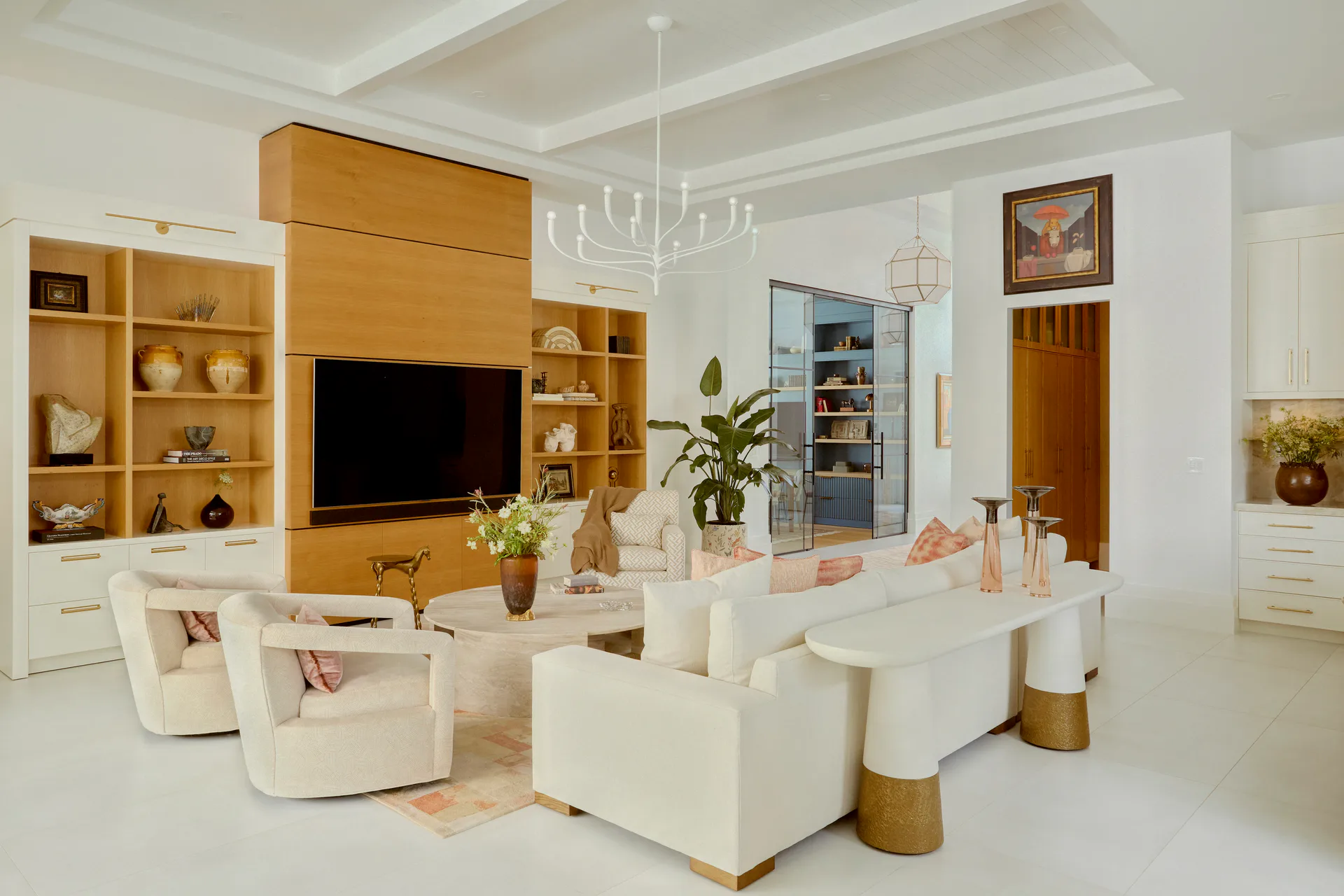 Modern living room with wooden built-in cabinetry, cream upholstered seating, and minimalist décor by Russell Goldman.
