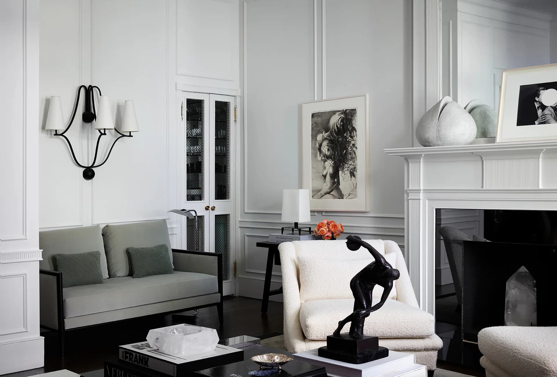 Modern living room with gray sofa, black sculptural figure, white fireplace, and minimalist furnishings in neutral palette by Ryan Korban.
