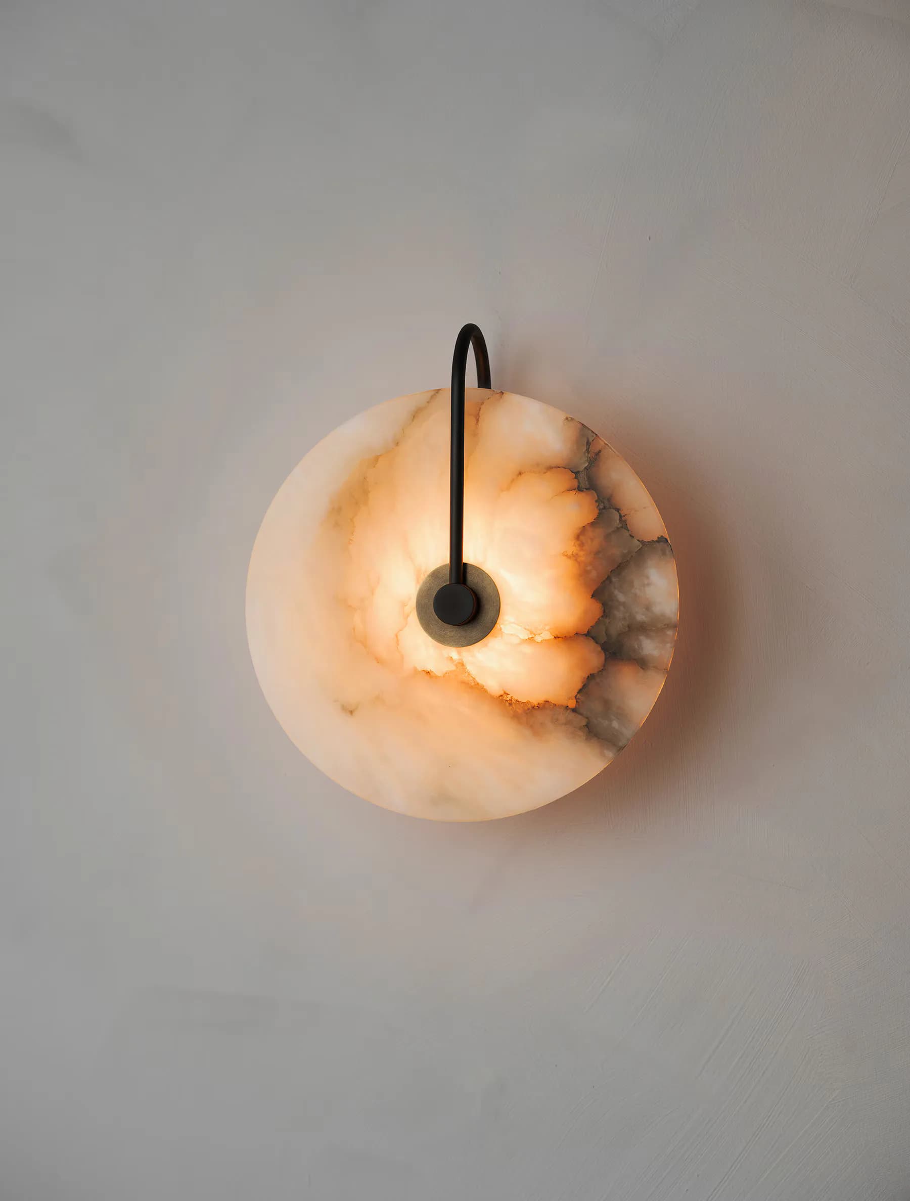 Spherical wall-mounted clock with warm amber and cream resin or stone finish, black hands and center detail by Ryden Rizzo.