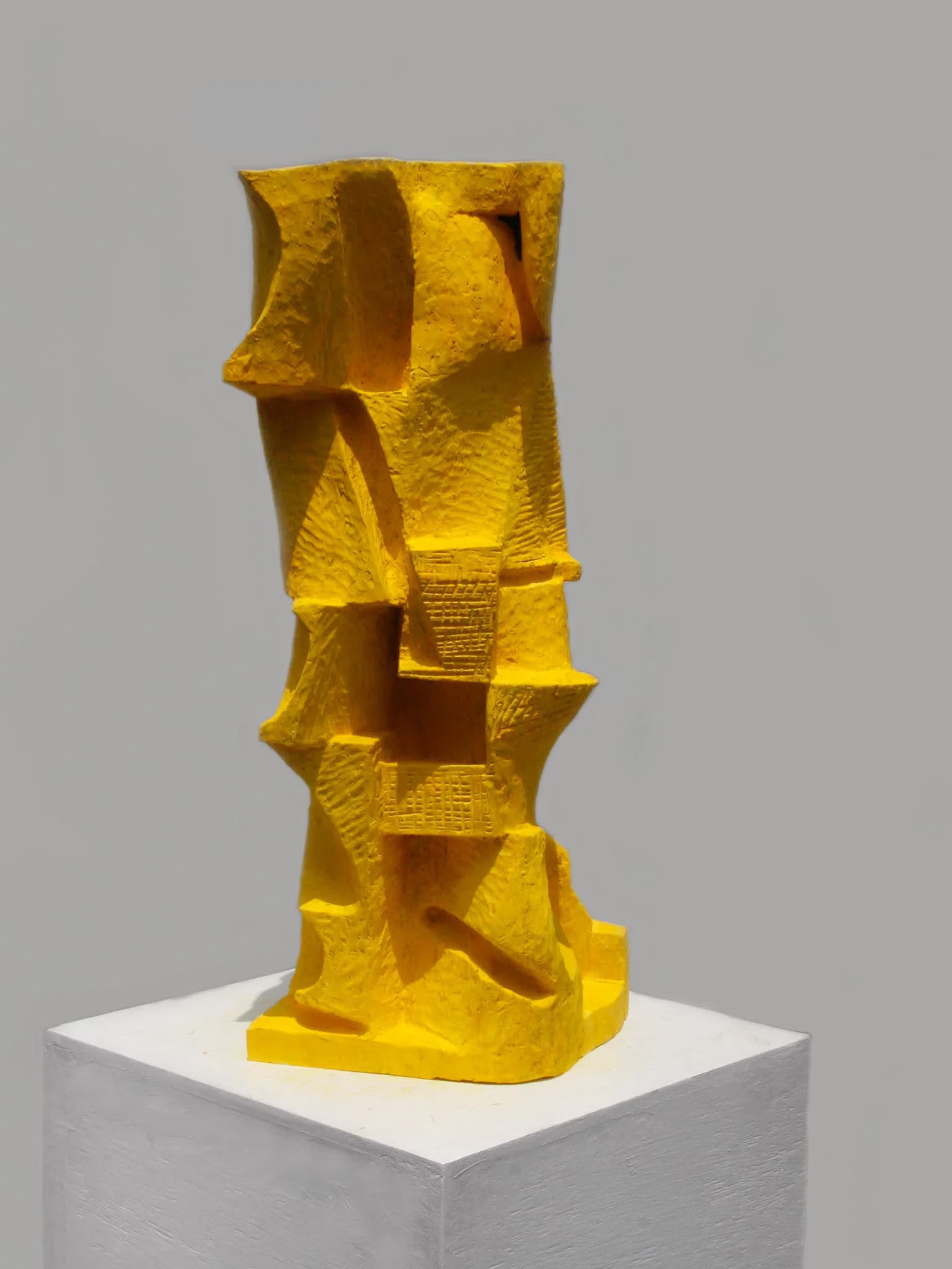 Bright yellow sculptural installation with geometric cutouts and layered forms mounted on a white pedestal, by Ryosuke Yazaki.