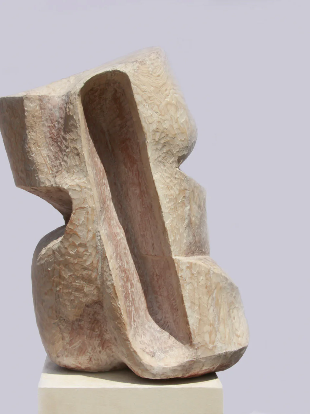Abstract stone sculpture featuring cream and brown carved forms with curved, organic surfaces mounted on a white pedestal by Ryosuke Yazaki.