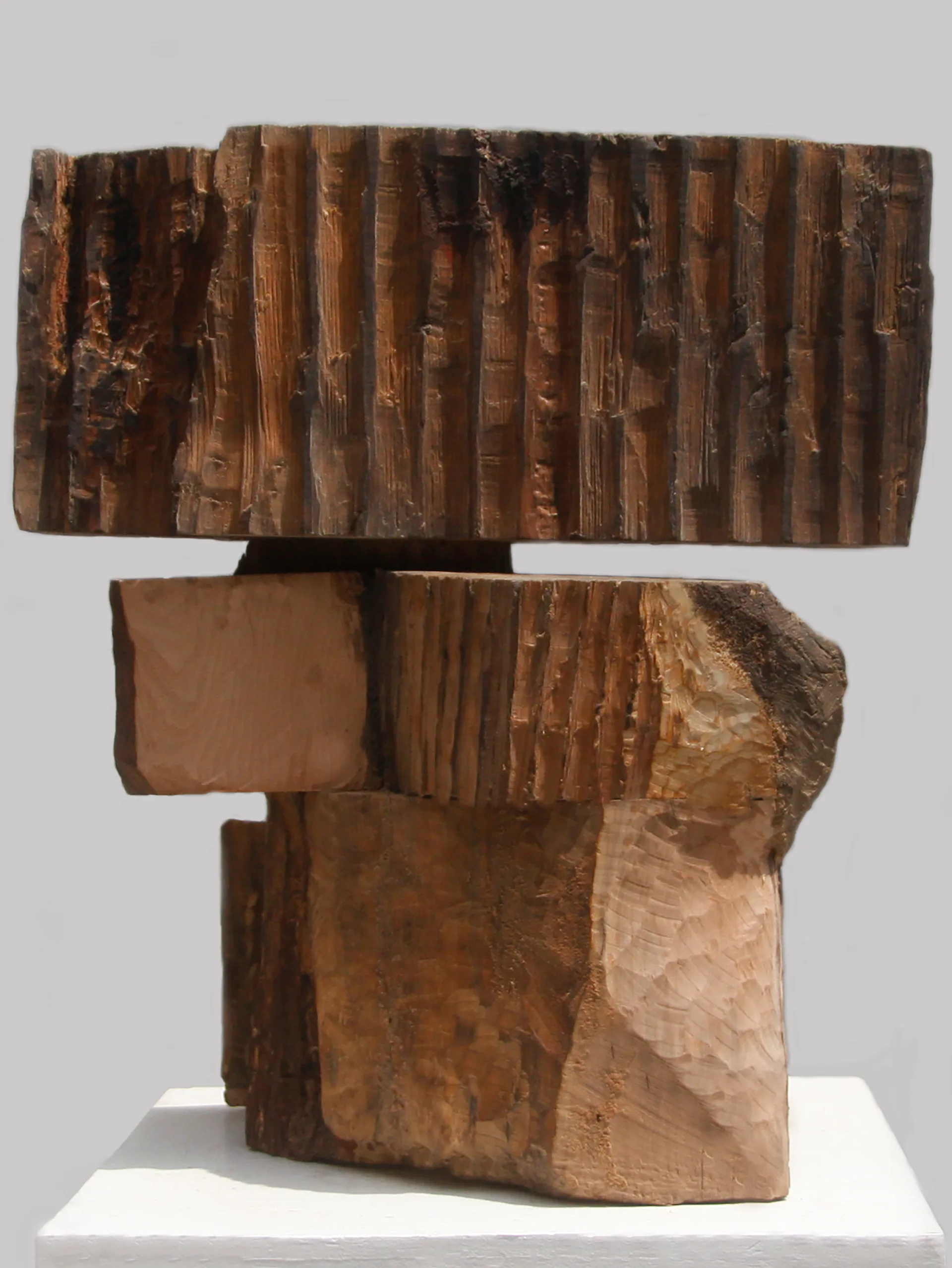 Abstract wooden sculpture with stacked rectangular forms and layered vertical grain patterns in warm brown tones by Ryosuke Yazaki.