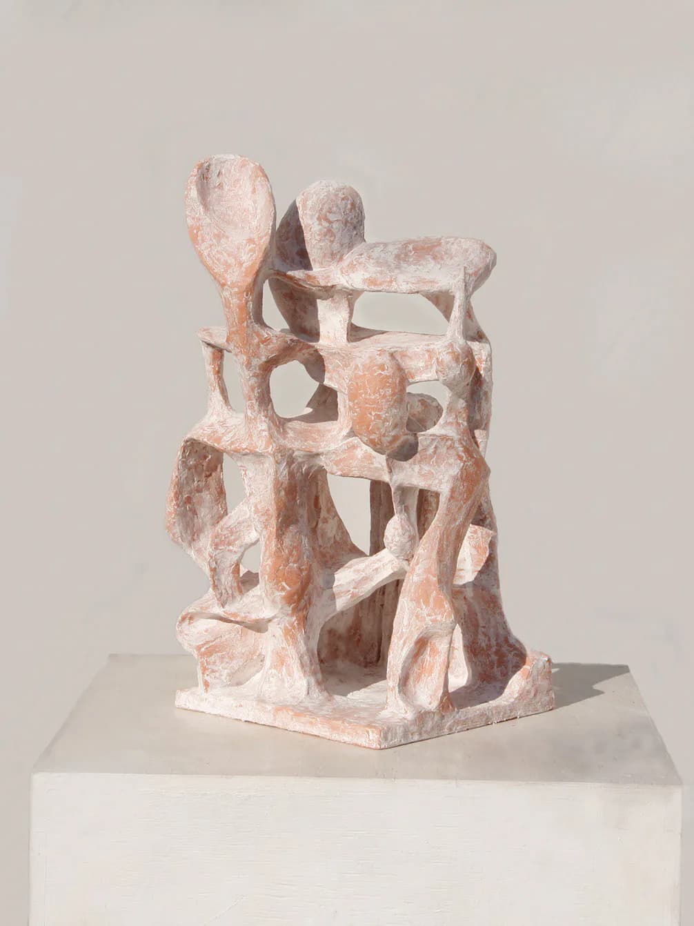 Abstract sculptural installation in terracotta and white tones with organic, interconnected geometric forms on a white pedestal by Ryosuke Yazaki.
