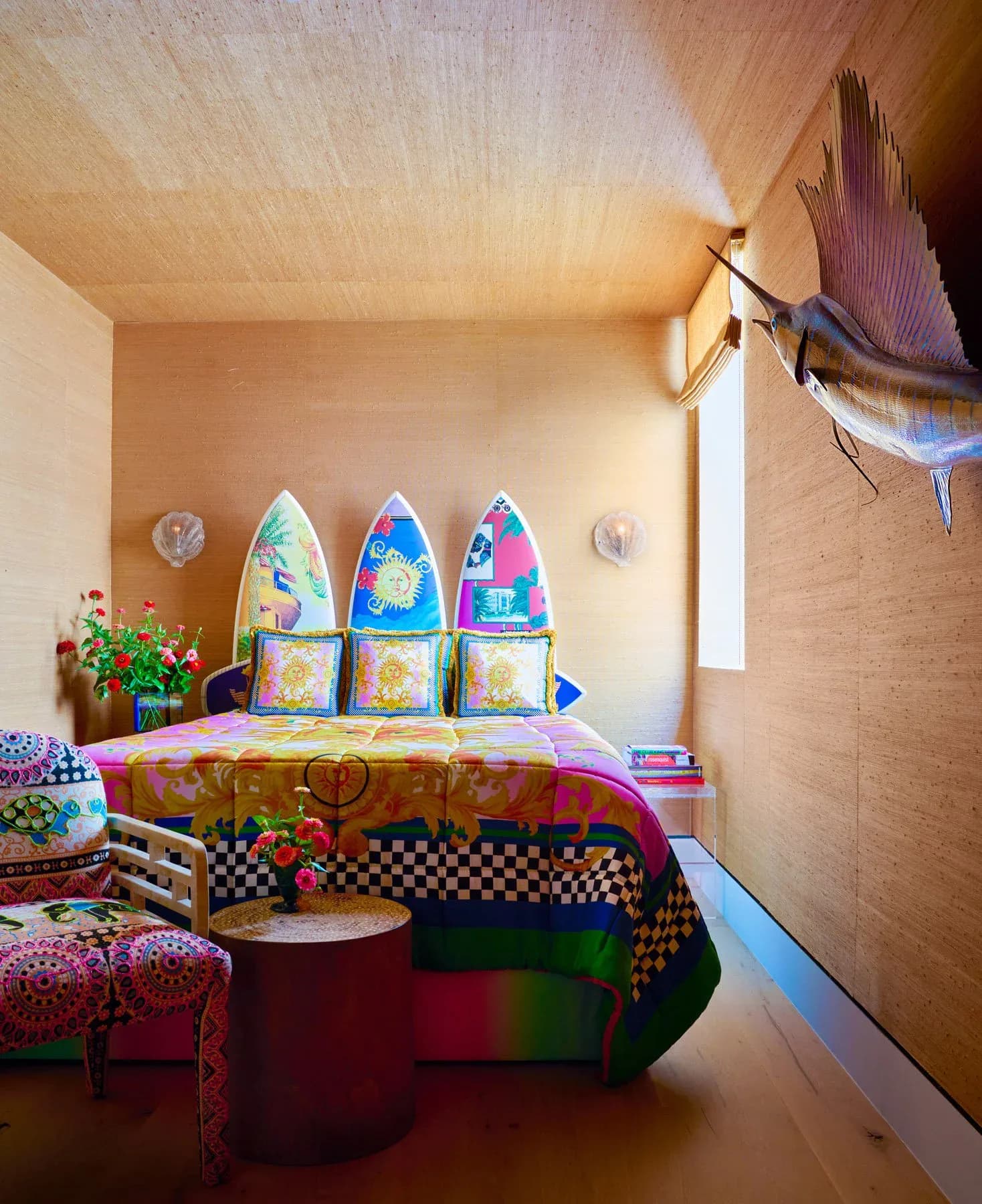 Colorful eclectic bedroom with toy rocket sculptures, patterned textiles, checkered details, and vibrant furnishings by Sasha Bikoff.