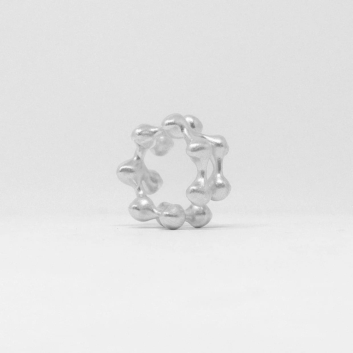 Silver metallic sculptural bracelet or ring composed of interconnected spheres and geometric forms arranged in a circular composition by Sebastian Bidegain.