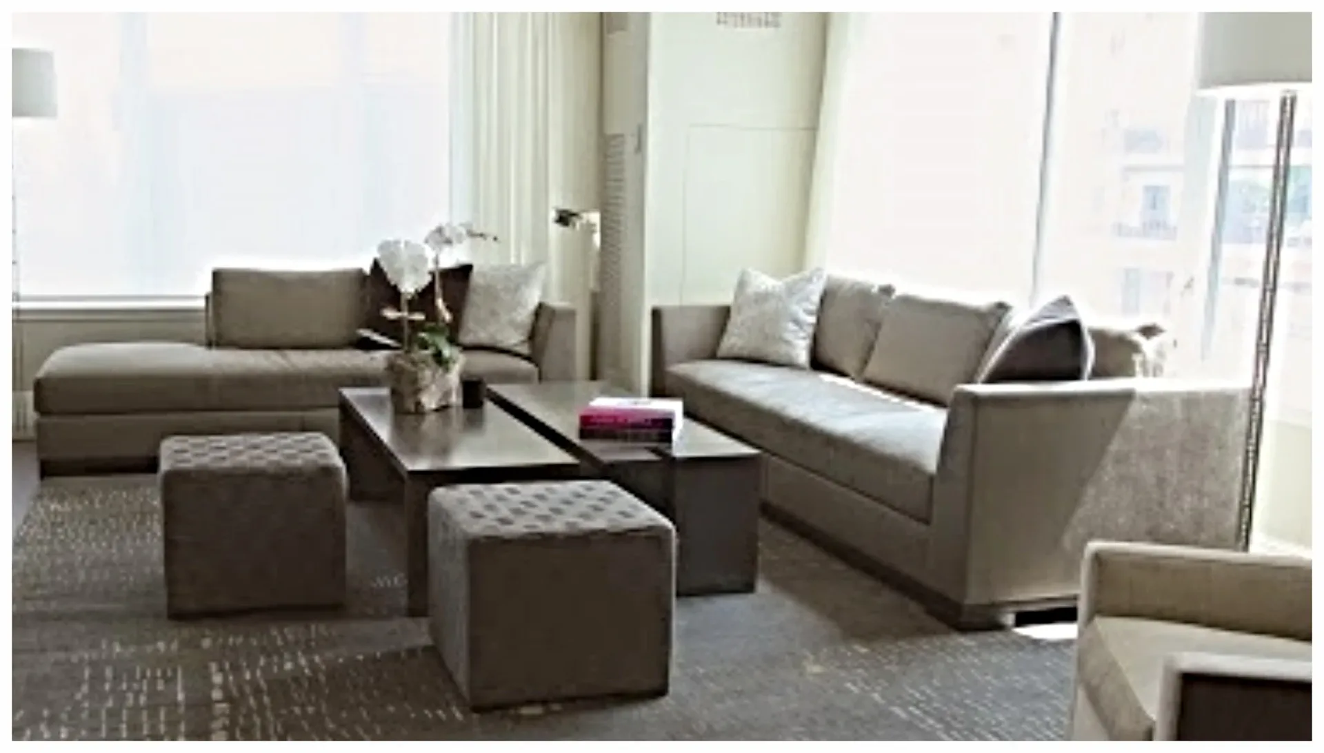 Contemporary living room with taupe upholstered sectional sofa, geometric patterned ottomans, black coffee table, and neutral palette by Sherry Brous.