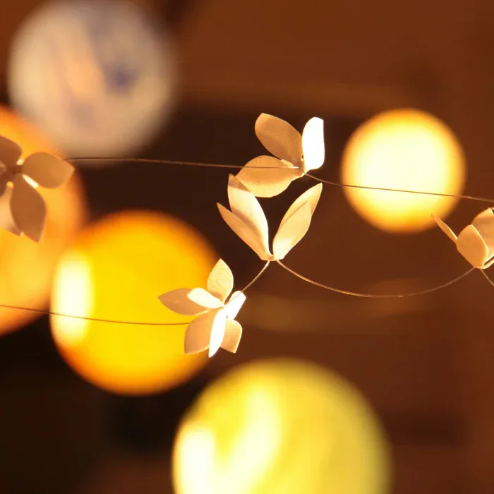 Abstract CGI rendering of glowing spheres and delicate botanical elements suspended against a warm brown background, featuring synthetic lighting and impossible spatial composition by Simi Avidan.