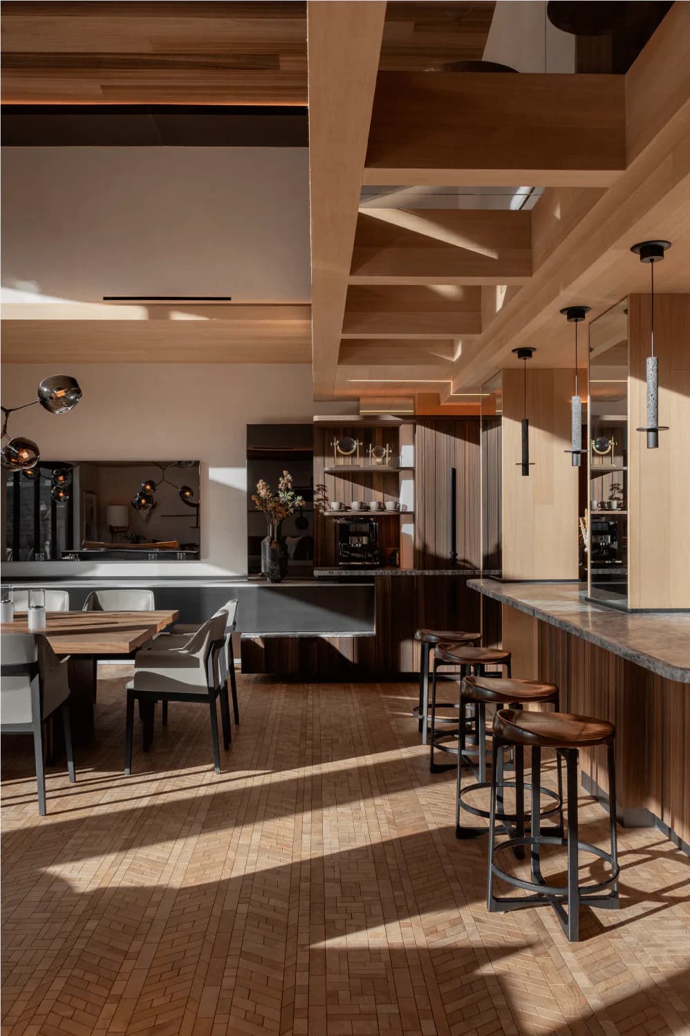 Contemporary open-plan kitchen and bar with wood ceiling details, dark cabinetry, concrete countertops, and bar seating by Simon Hamui.