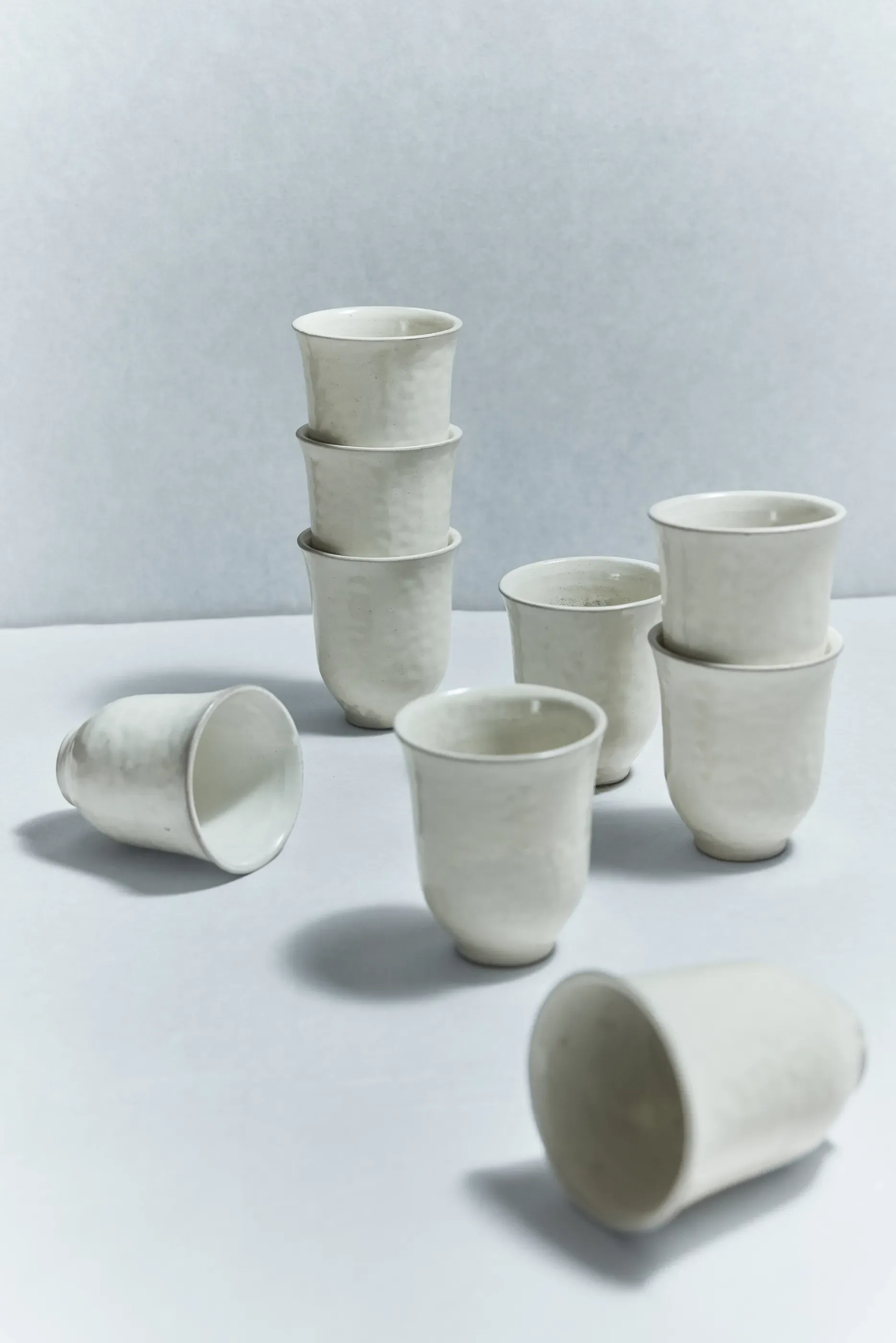 Minimalist ceramic vessels in off-white stoneware arranged in a composed still life, showcasing functional pottery design by Simone Bodmer-Turner.