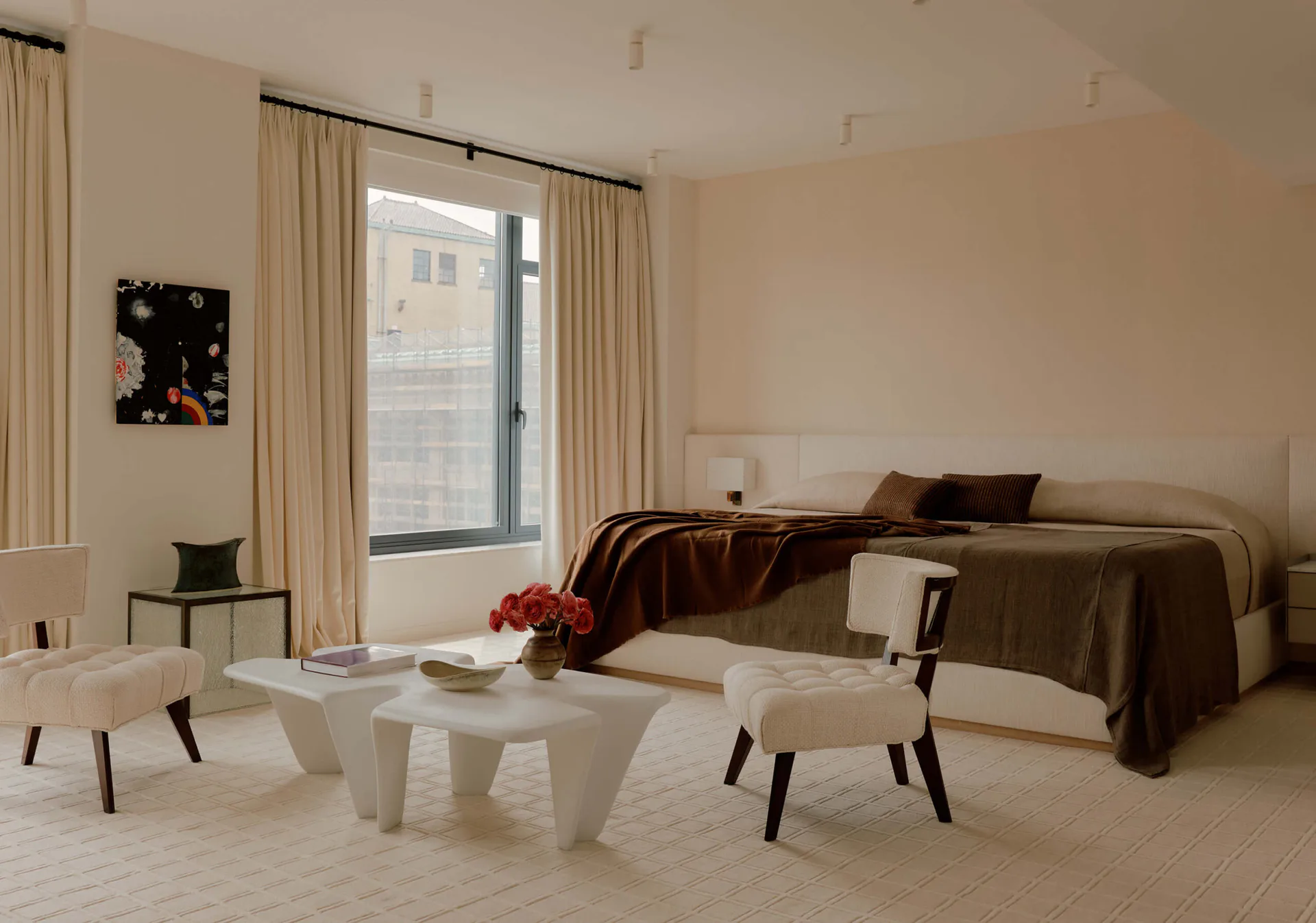 Minimalist bedroom with neutral palette, curved olive sofa, cream sculptural side tables, and floor-to-ceiling windows by Soo Chung.