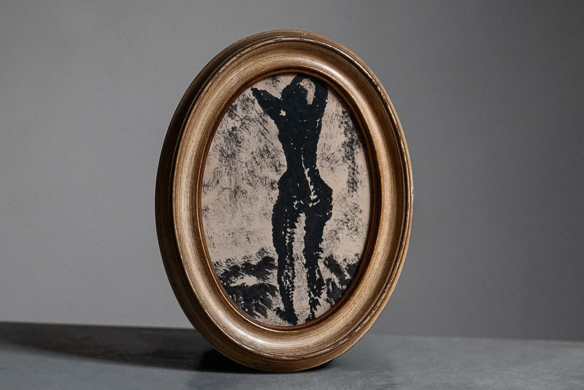 Oval-framed vintage-style portrait featuring a silhouetted figure against a textured background, with ornate bronze frame, design work by Stefania Papadakis.
