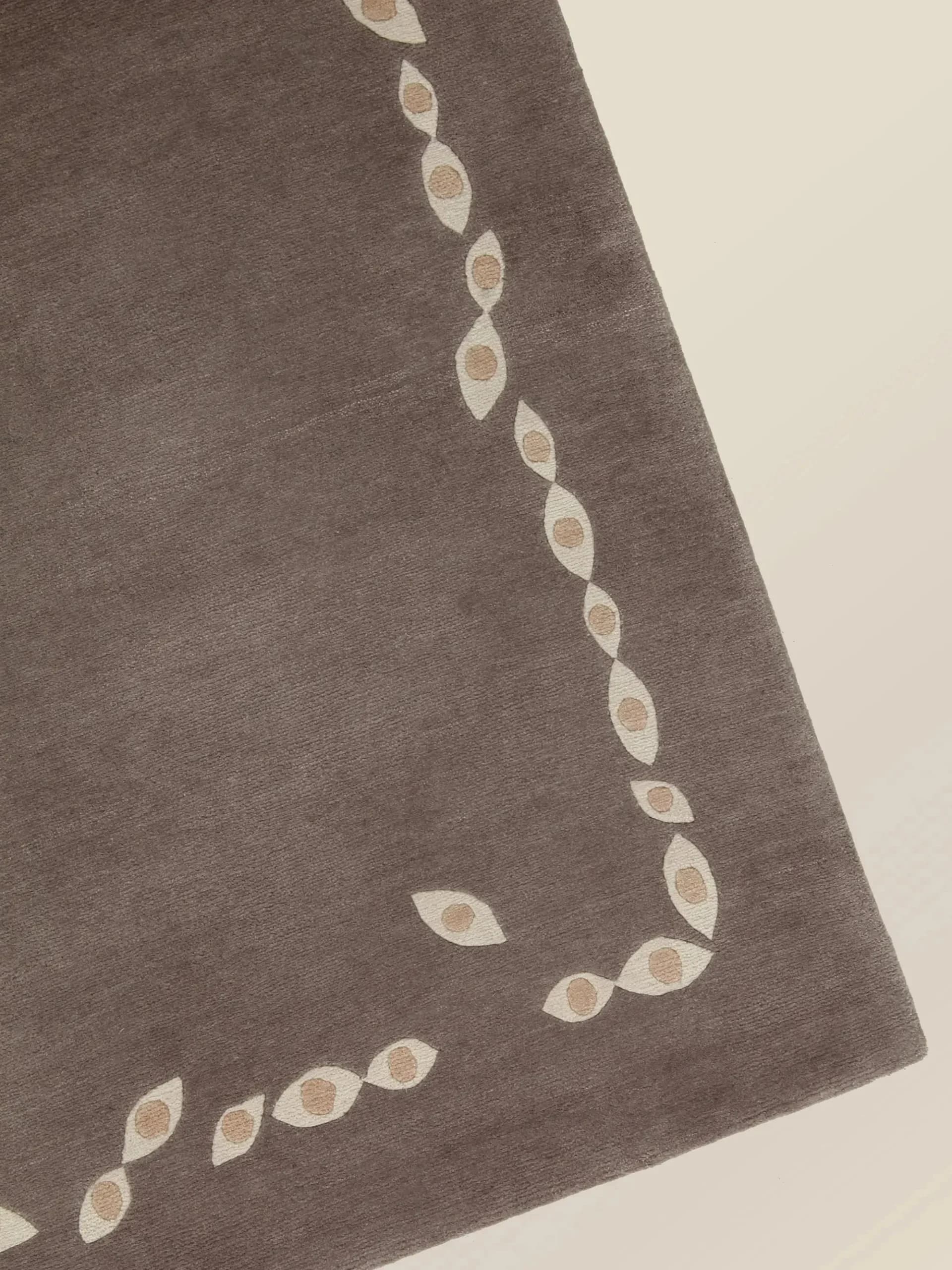 Charcoal-gray fabric garment with delicate cream leaf-motif embroidery forming curved lines down the front, by Stephanie Beamer.