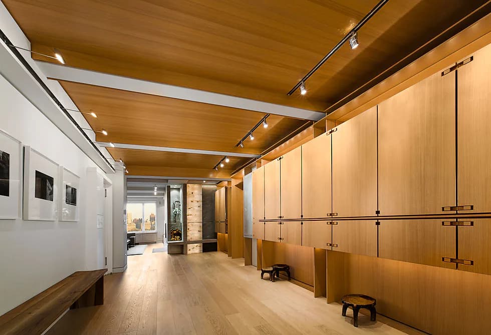 Contemporary interior hallway featuring warm wood ceiling beams, light oak cabinetry, polished concrete flooring, and track lighting, designed by Stephen Lee.