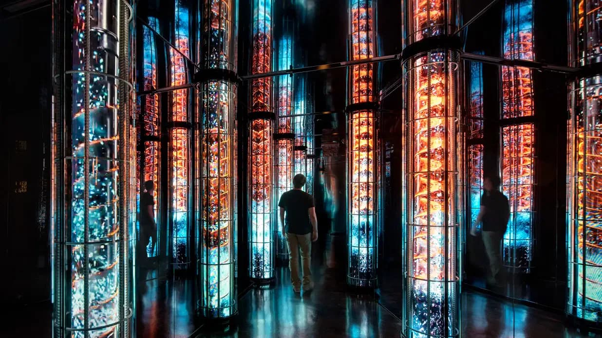 Dark interior installation featuring tall vertical light columns in red and blue neon, with silhouetted figures moving through the illuminated space by Sunmi Lee.