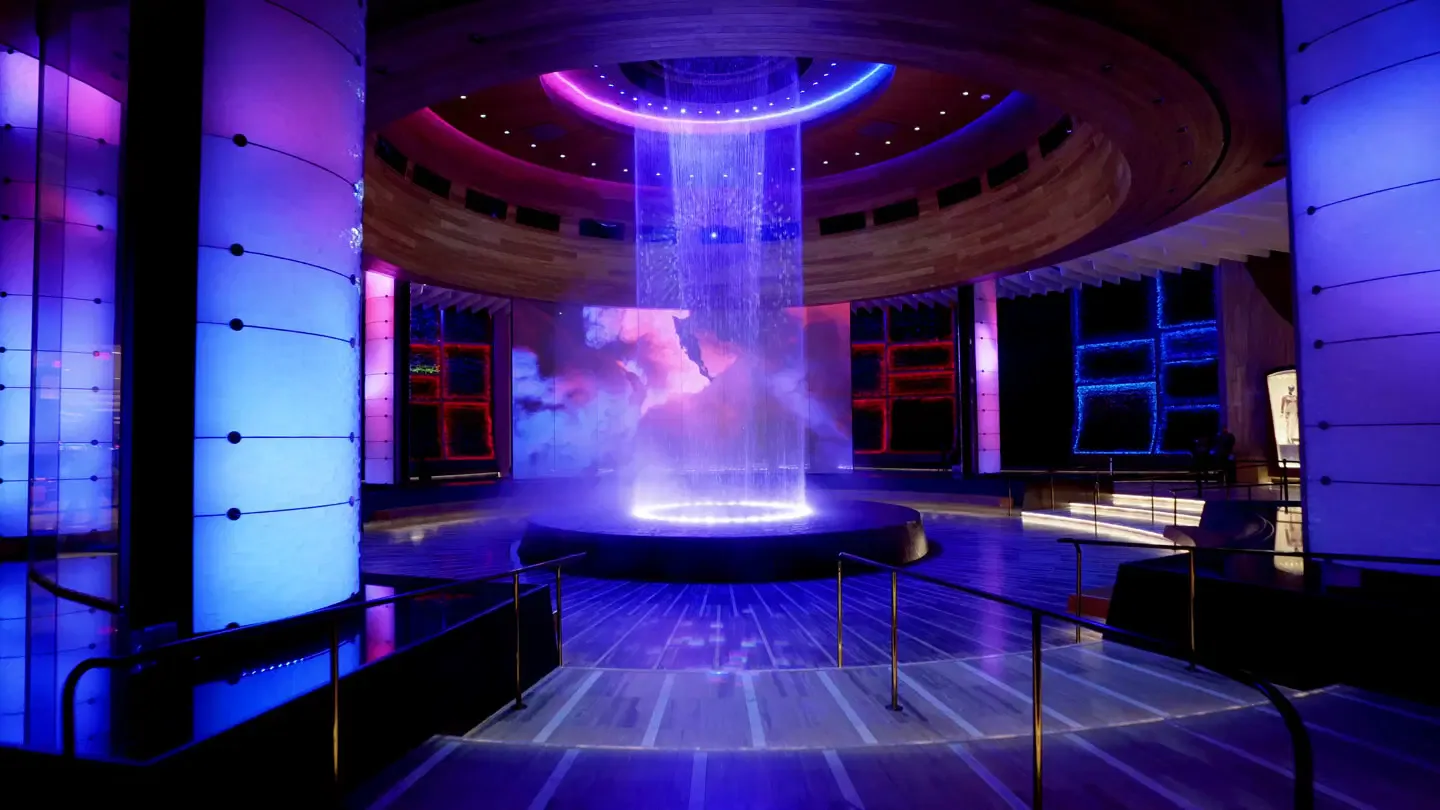Futuristic nightclub interior with neon purple and blue lighting, circular ceiling design, and glowing central installation by Sunmi Lee.