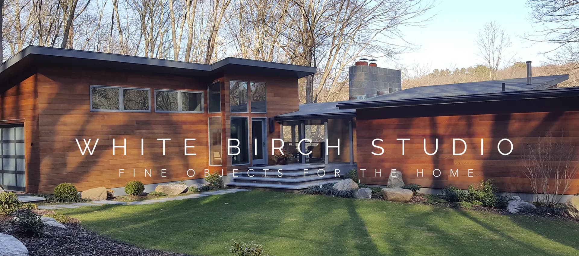 Modern mid-century residential architecture with warm wood siding, expansive glazing, and manicured lawn, photographed at golden hour by Susan Anderson.