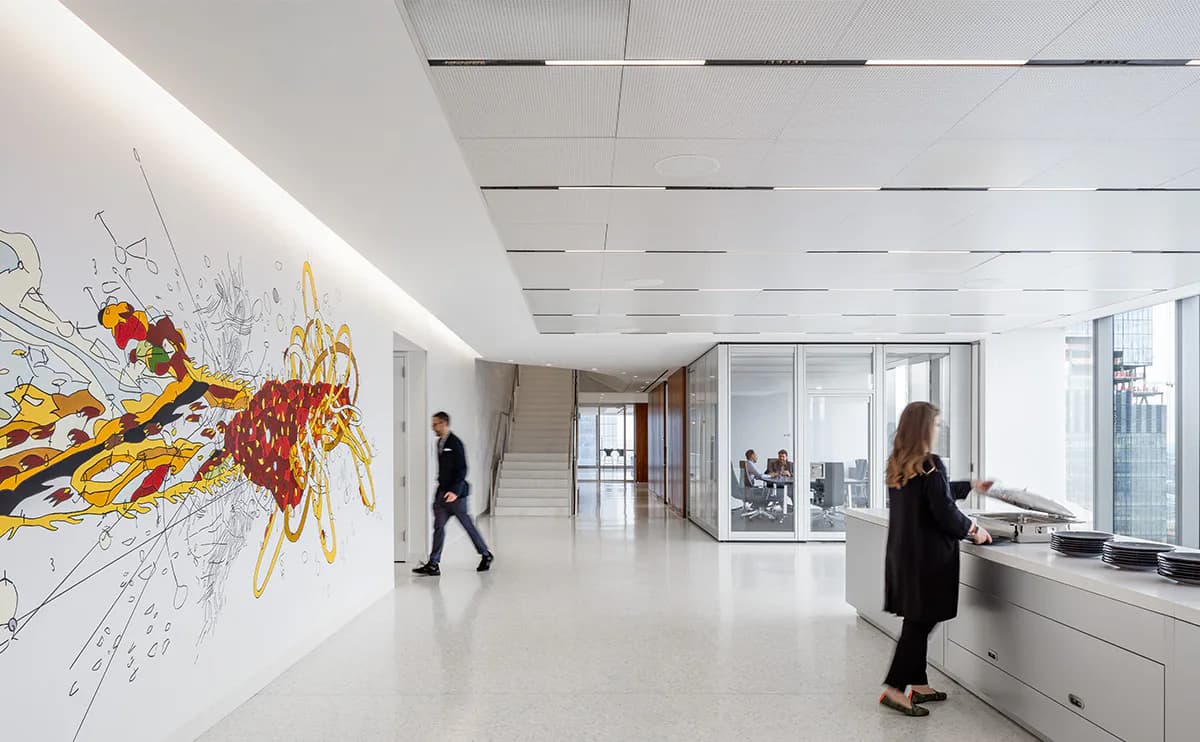 Bright modern office lobby with polished concrete floors, white ceiling with recessed lighting, and a large abstract yellow and red artwork on the left wall by Susan Brady.