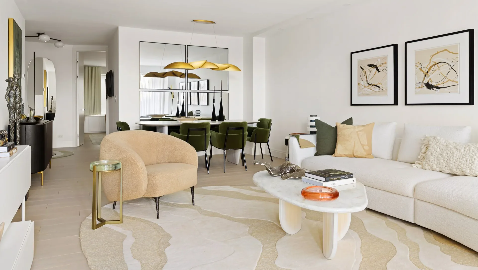 Modern living room with cream and green palette, curved furniture, gold pendant lighting, and white sculptural coffee table by Susan Hughes.