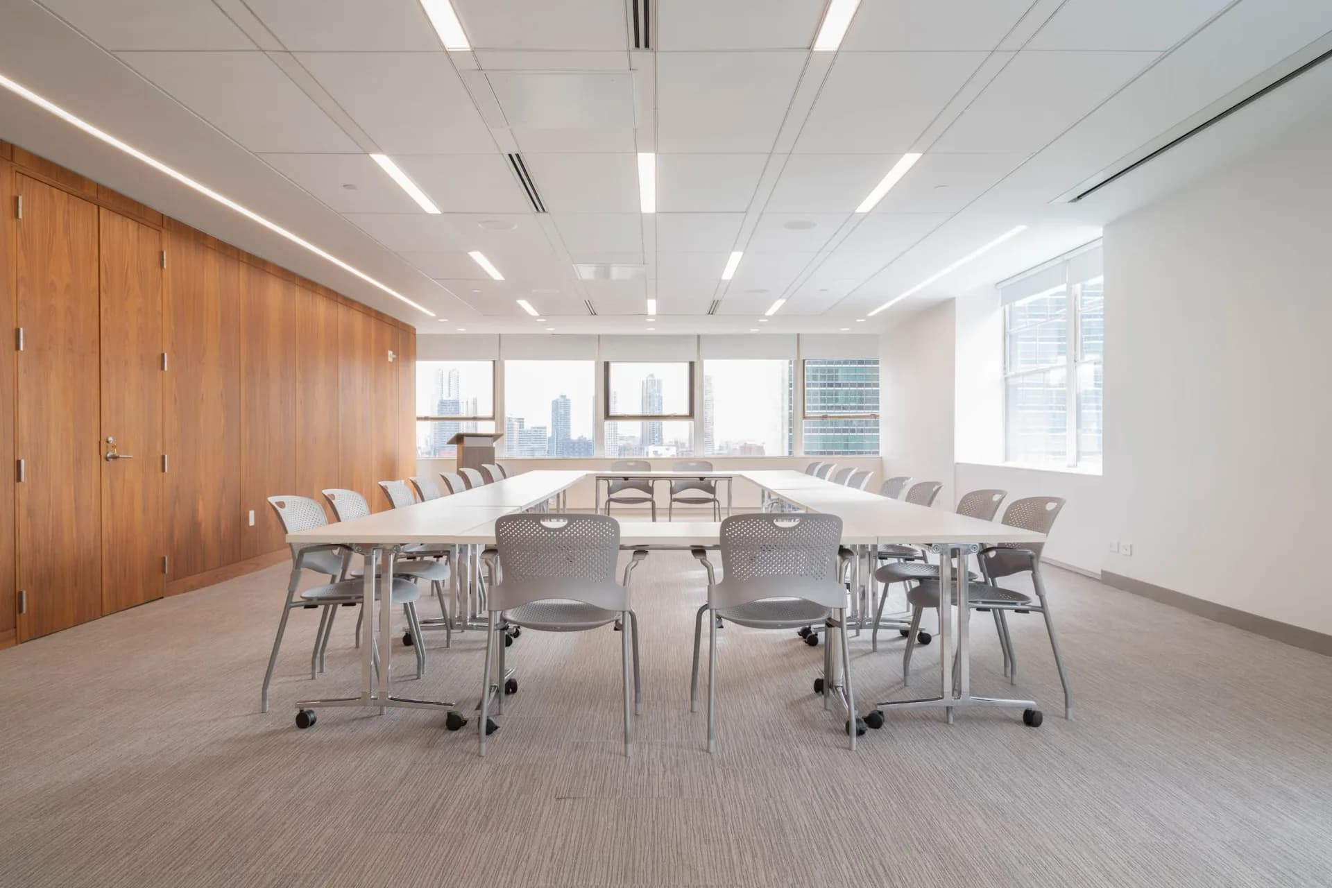 Modern conference room with U-shaped table, mobile chairs, wooden cabinetry, and floor-to-ceiling windows by Susan Torenli.