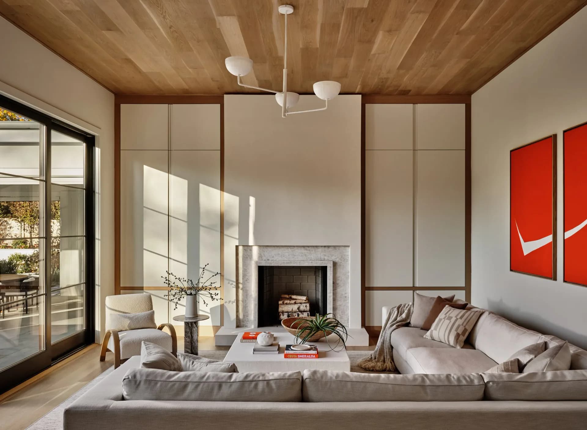 Modern living room with wood ceiling, gray sectional sofa, fireplace, and red artwork features synthetic lighting and perfect material uniformity characteristic of architectural CGI by Susana Simonpietri.