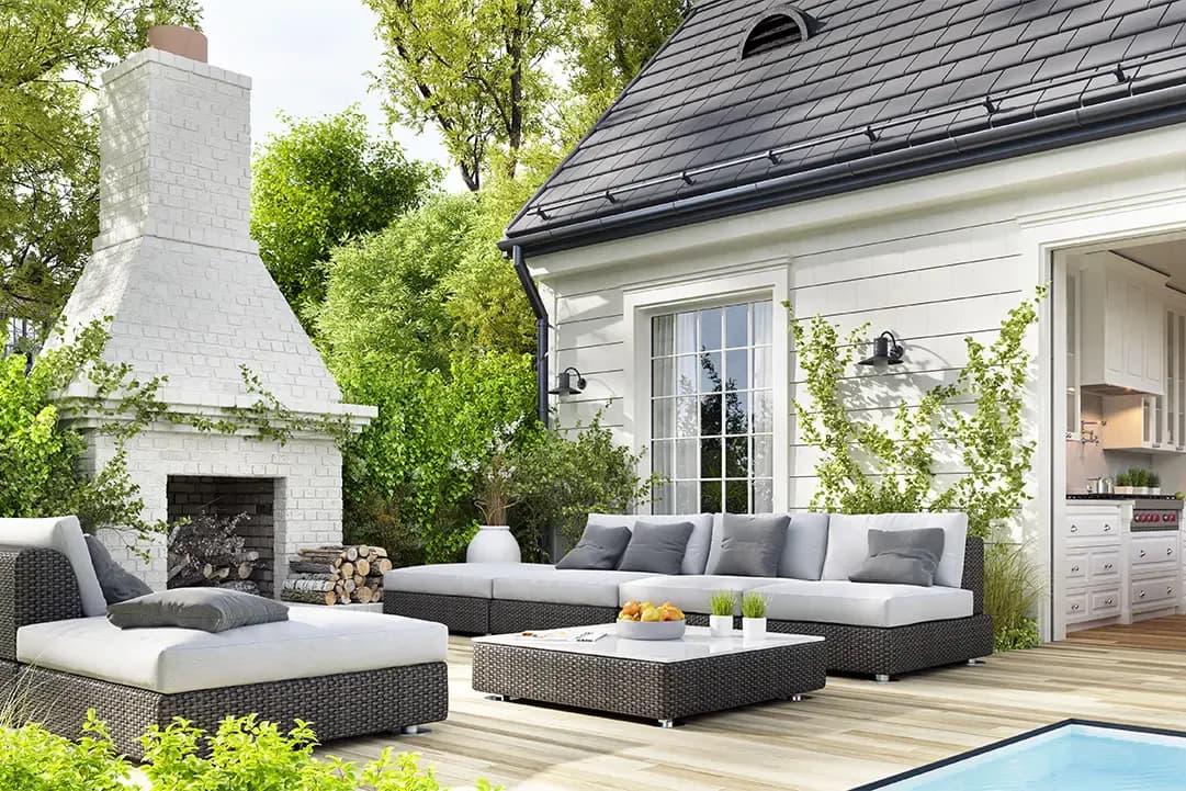 Modern outdoor patio with sectional seating, fireplace, and architectural house by Tarena Cernuto features crisp synthetic lighting and pristine material repetition typical of CGI rendering.