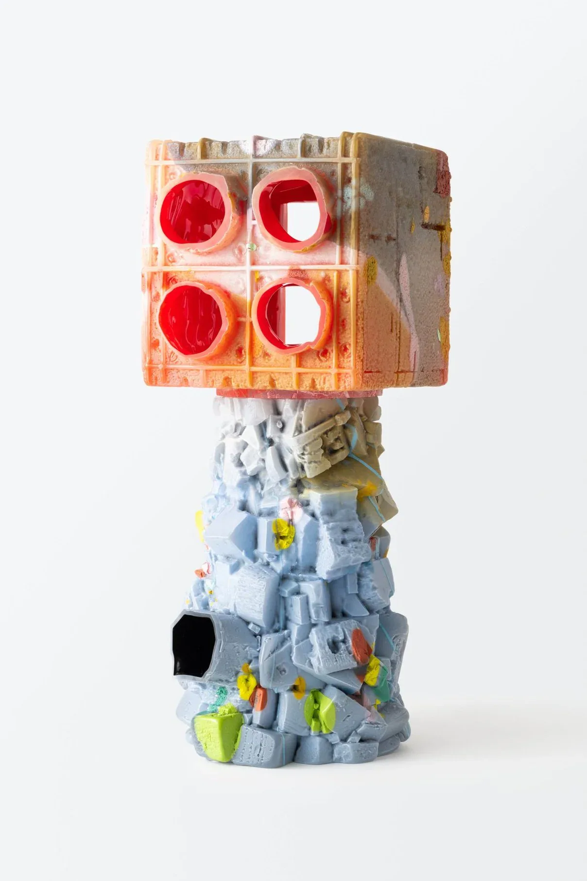 Stacked sculptural installation with translucent orange resin top featuring red circular elements, supported by textured gray and white base with yellow accents, by Thaddeus Wolfe.