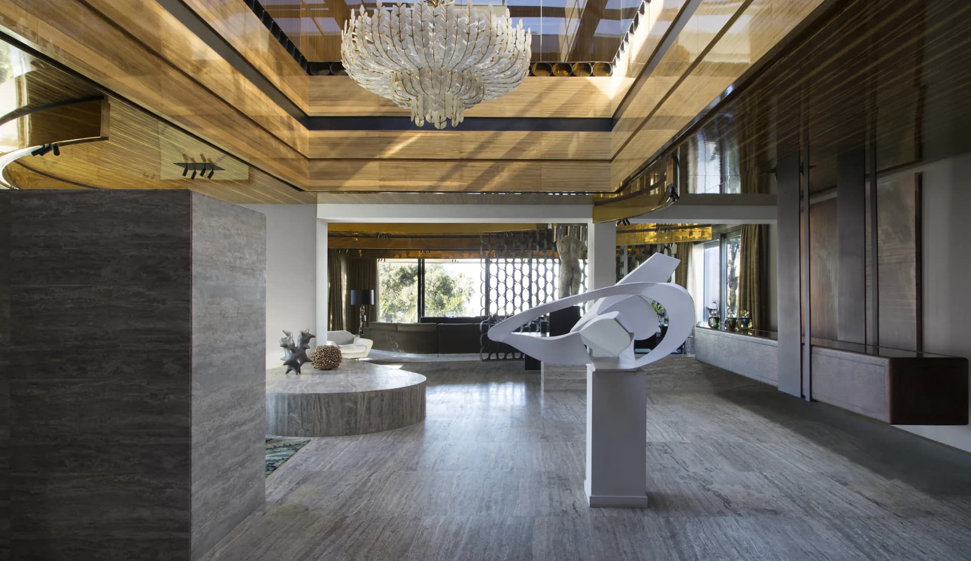 Modern lobby with warm wood ceiling, marble flooring, sculptural white form on pedestal, and minimalist dark paneling by Thierry Lemaire.