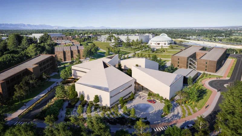 Aerial view of a modern institutional complex with cream and brick buildings arranged around landscaped grounds with water features and pathways, by Thomas Christoffersen.