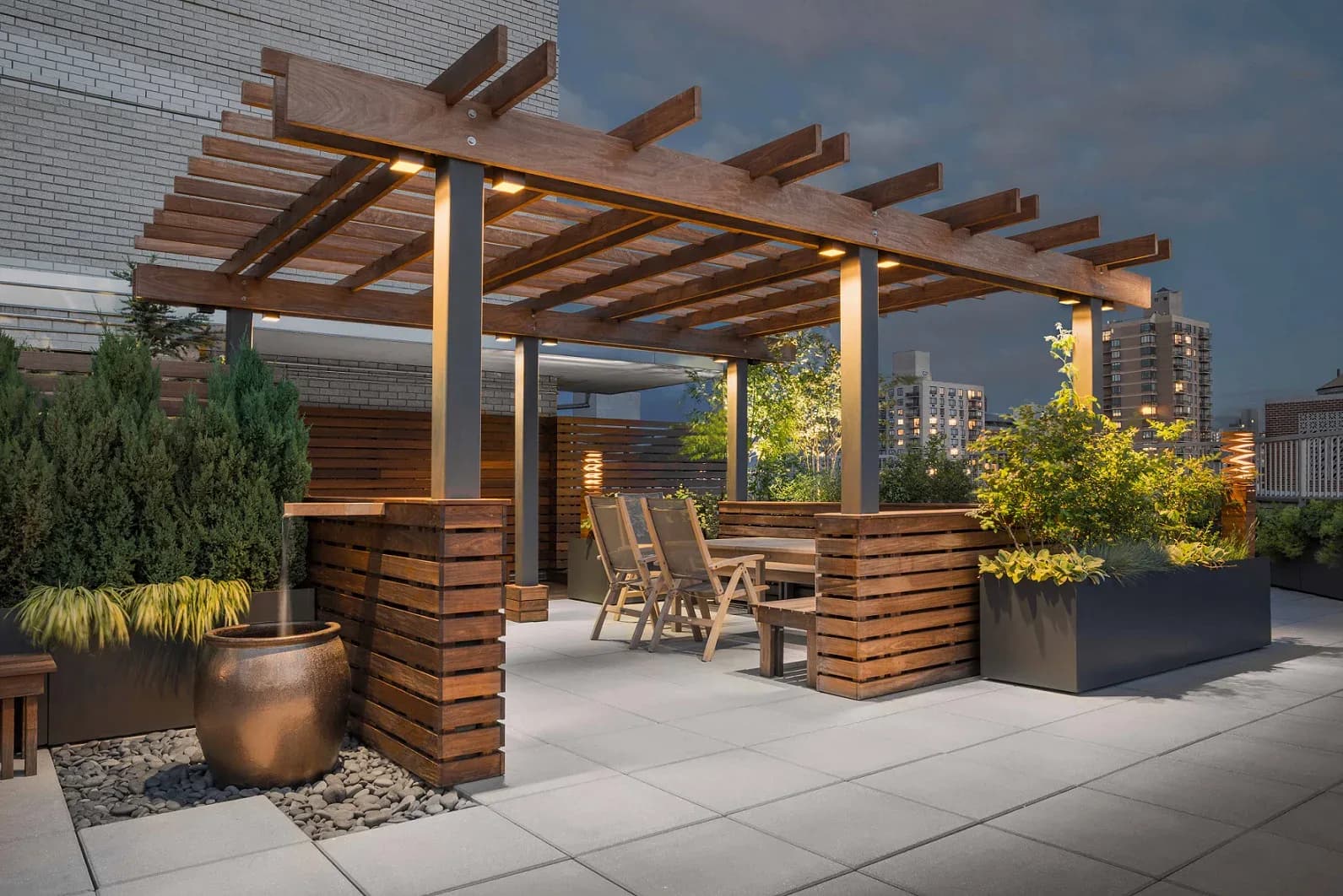 Modern rooftop terrace with wooden pergola, integrated seating, planters, and city skyline views, designed by Tillie O'Reilly.