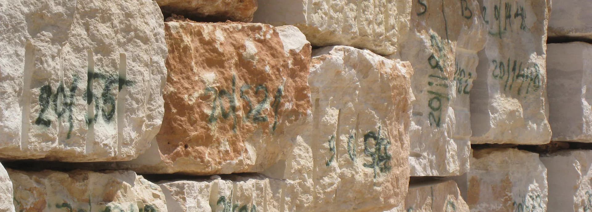 Stacked limestone blocks with weathered surfaces and green markings create a textured architectural detail, showcasing material craftsmanship by Tod Williams.