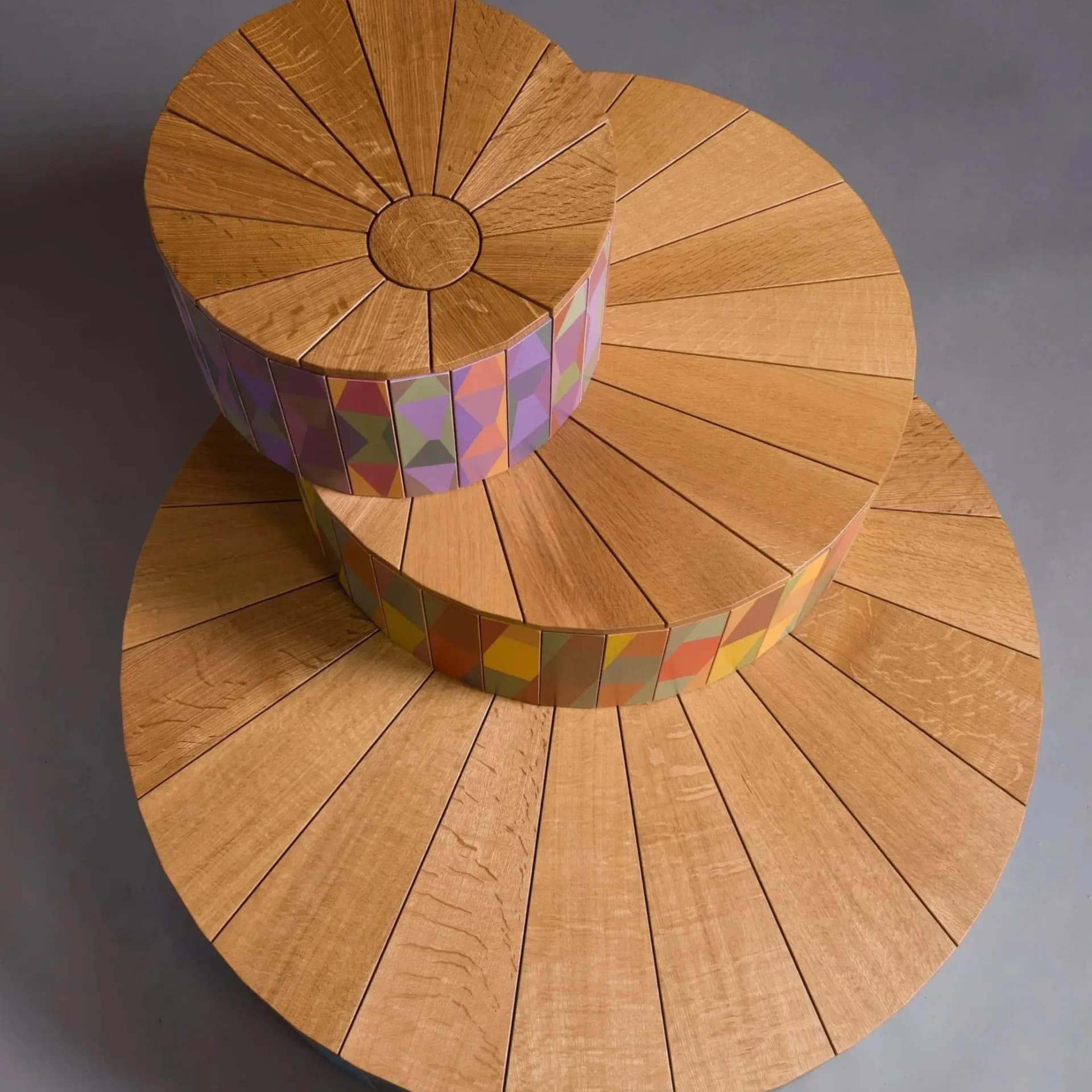 Stacked wooden circular platforms with radial segments and colorful fabric bands, sculptural furniture piece by Tom Loeser.