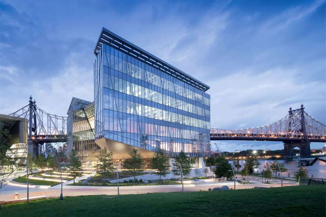 Modern waterfront office building with glass facade and integrated plaza featuring landscaping and waterfront views by Tomoko Akiba.